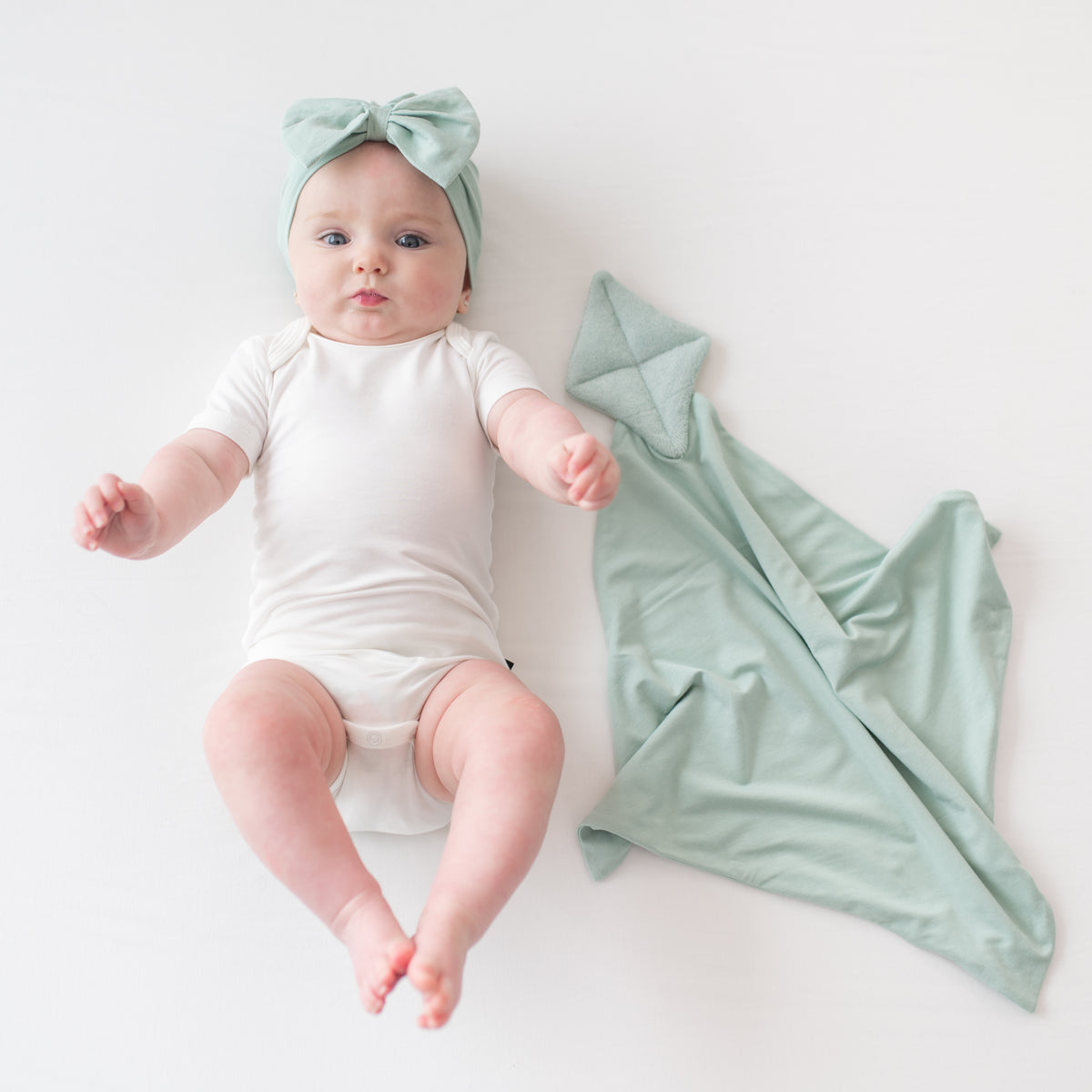 Baby wearing cloud bodysuit and Bow Headband in Sage next to Kite Lovey in Sage
