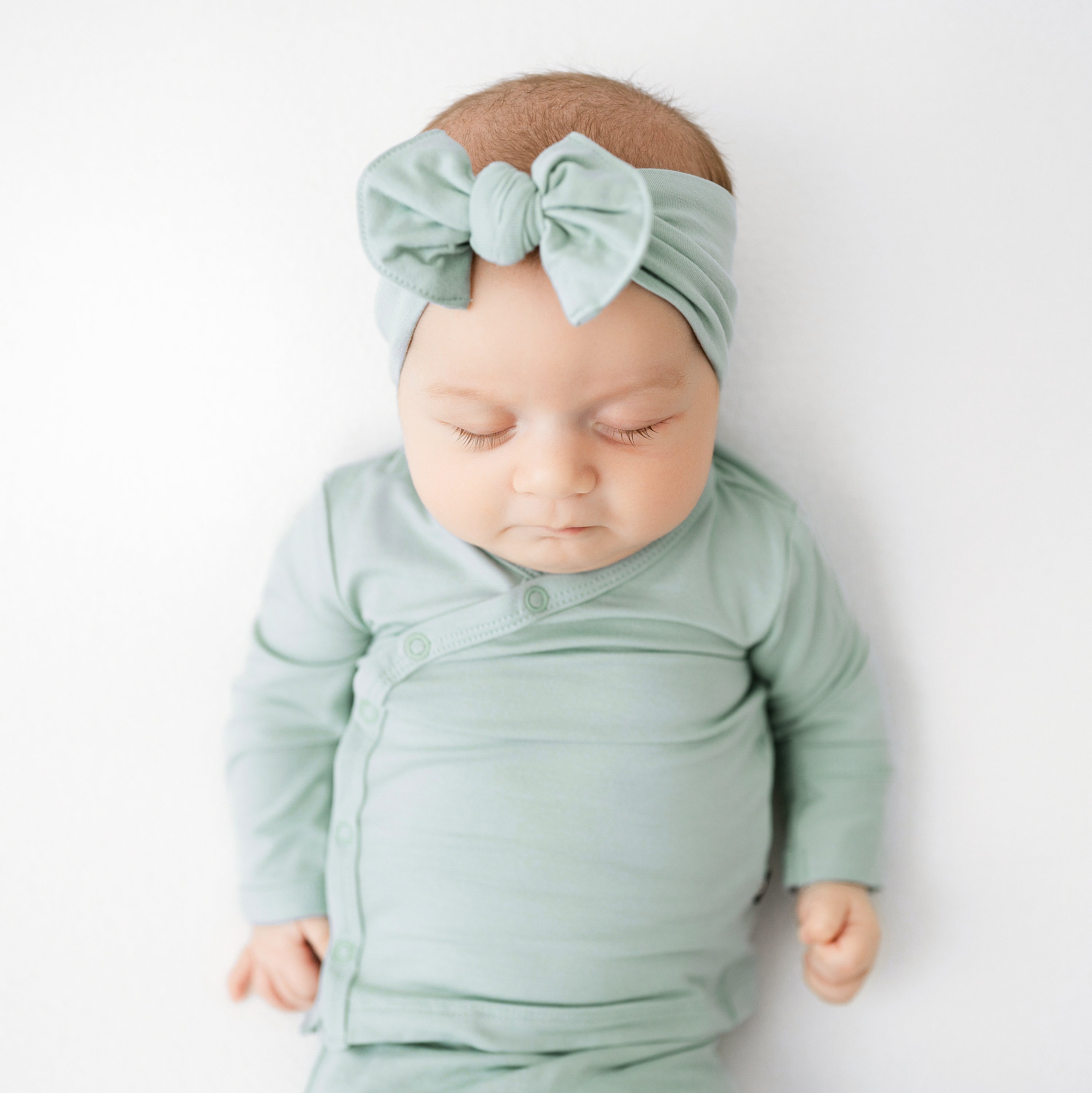 Sleeping baby wearing Knotted Bow Headband in Sage with matching Bundler