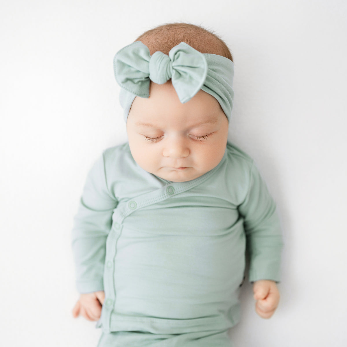 Sleeping baby wearing Knotted Bow Headband in Sage with matching Bundler