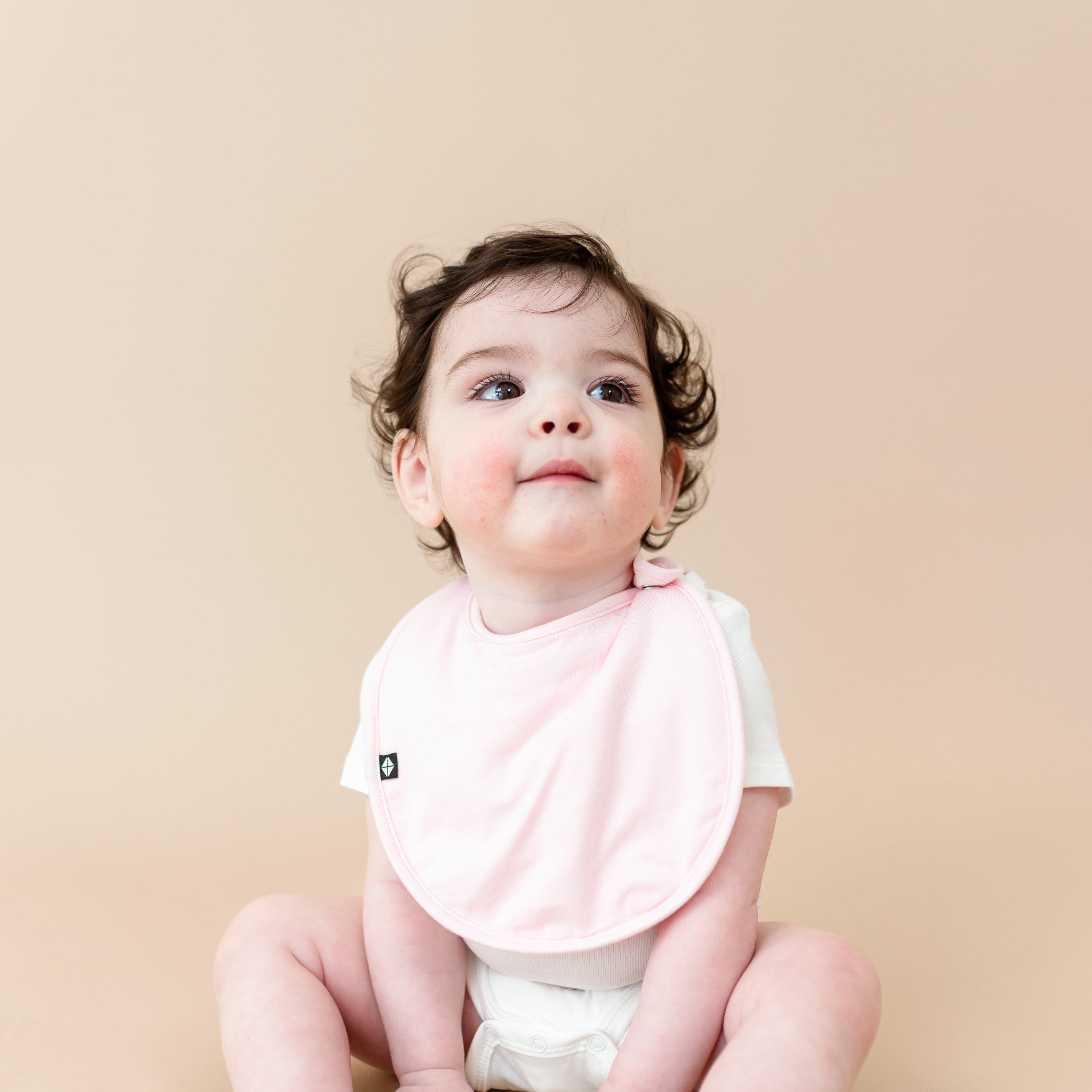 Baby wearing Cushy Bib in Sakura Pink