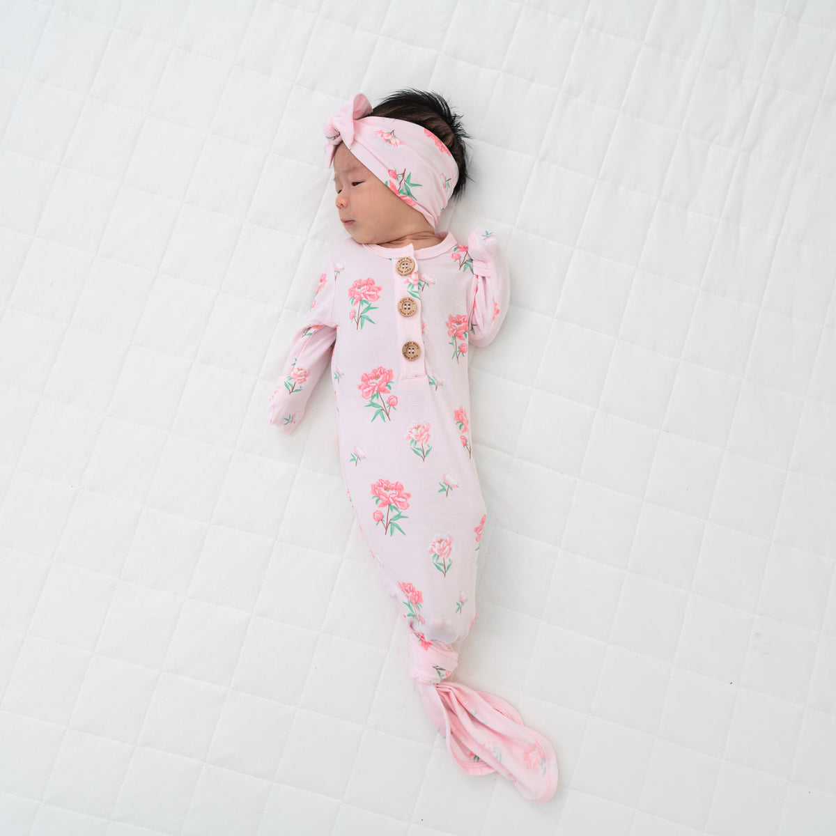 Newborn laying on a Cloud Blanket modeling the Knotted Gown with Bow Set in Sakura Peony