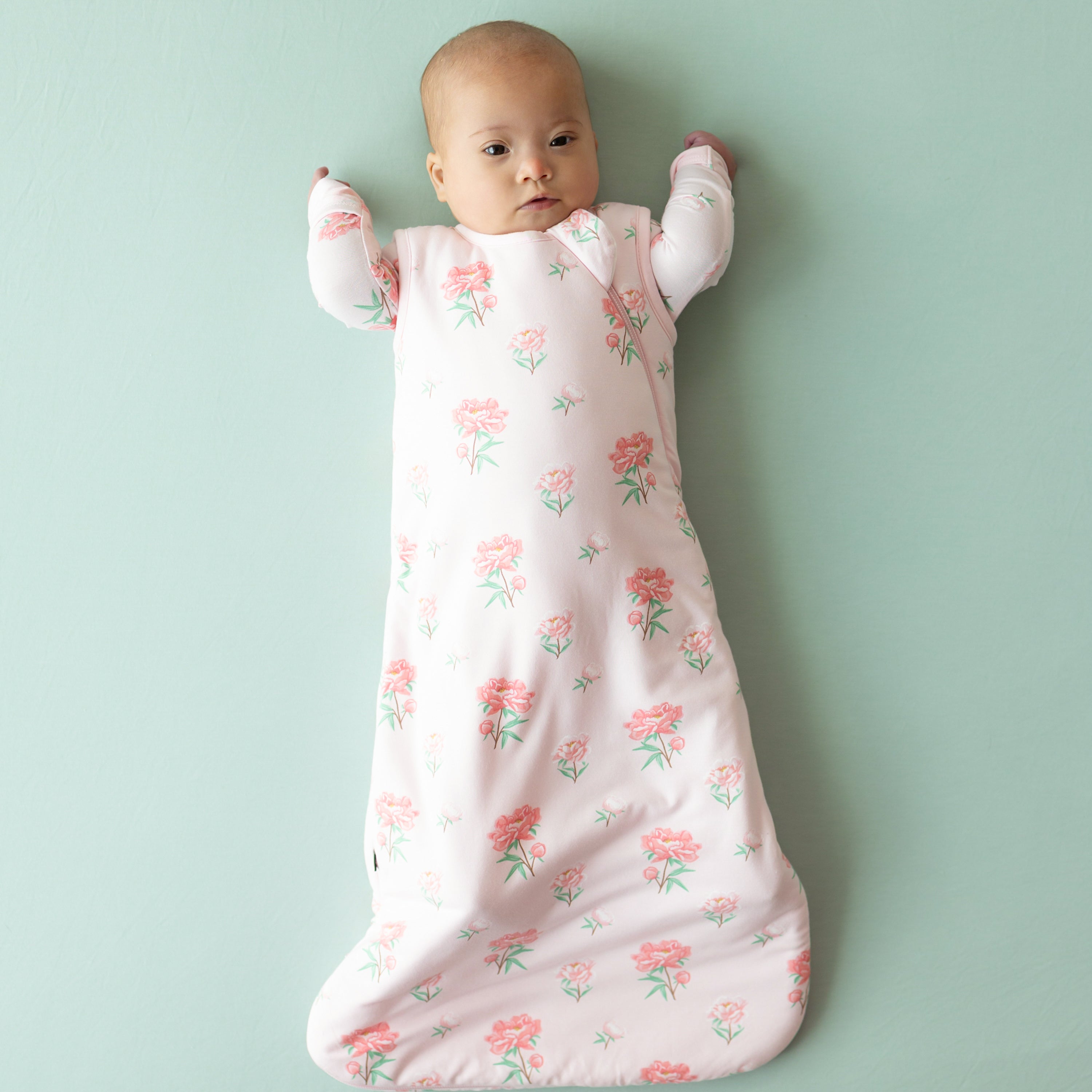 Infant model wearing the Sleep Bag in Sakura Peony with matching long sleeve romper underneath