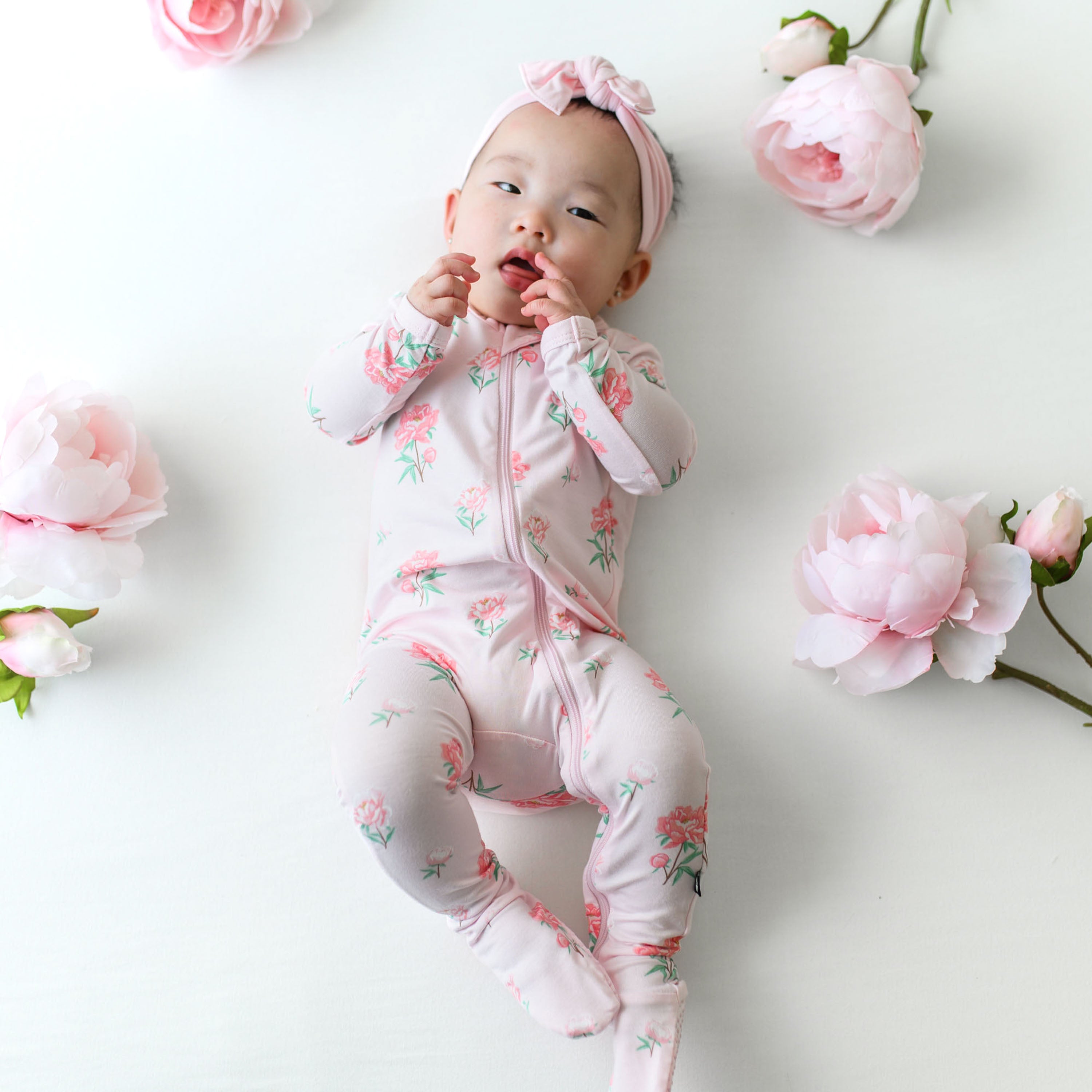 Infant wearing Zippered Footie baby pajamas in Sakura Peony pink