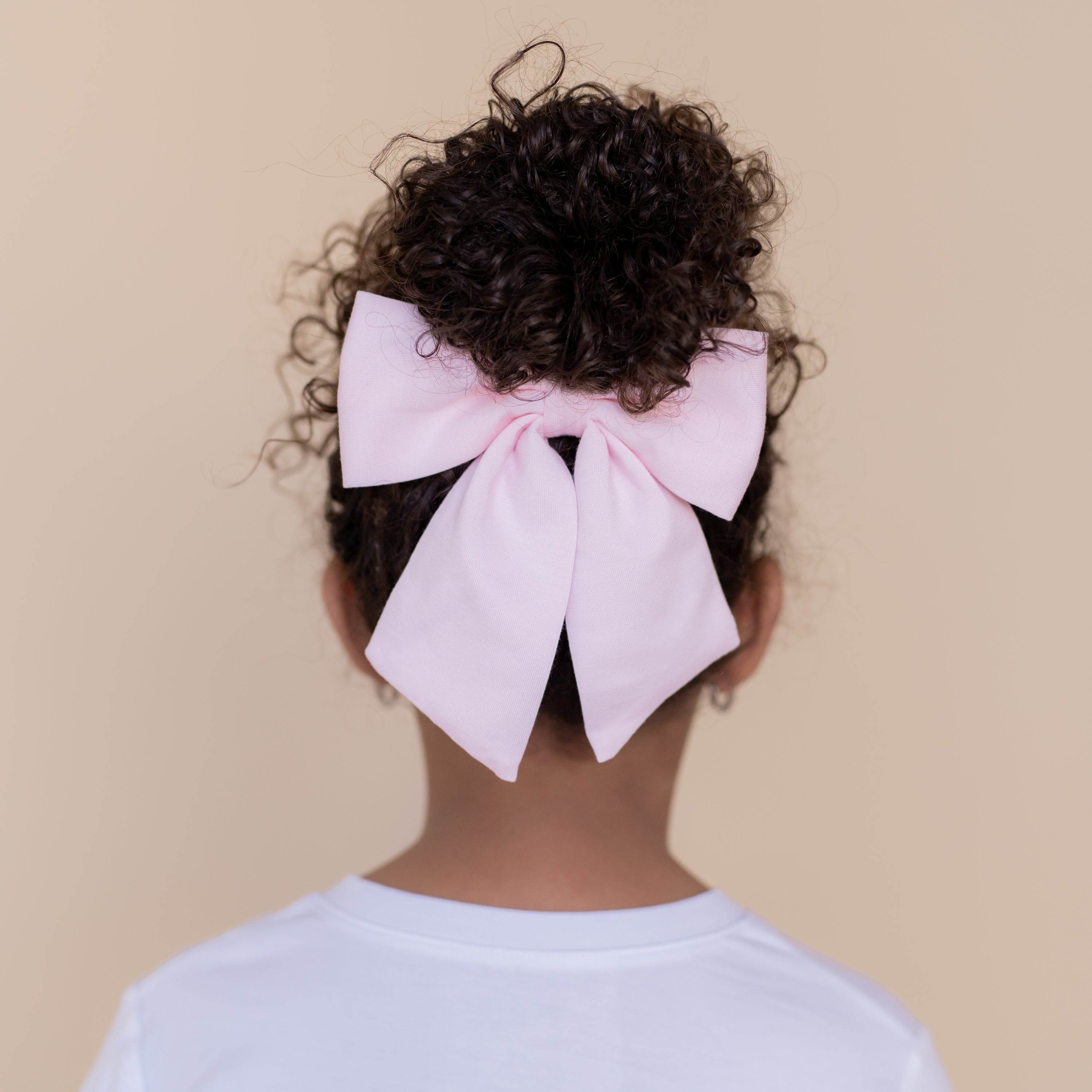 Large Alligator Clip Bow in Sakura shown in the hair of a young model