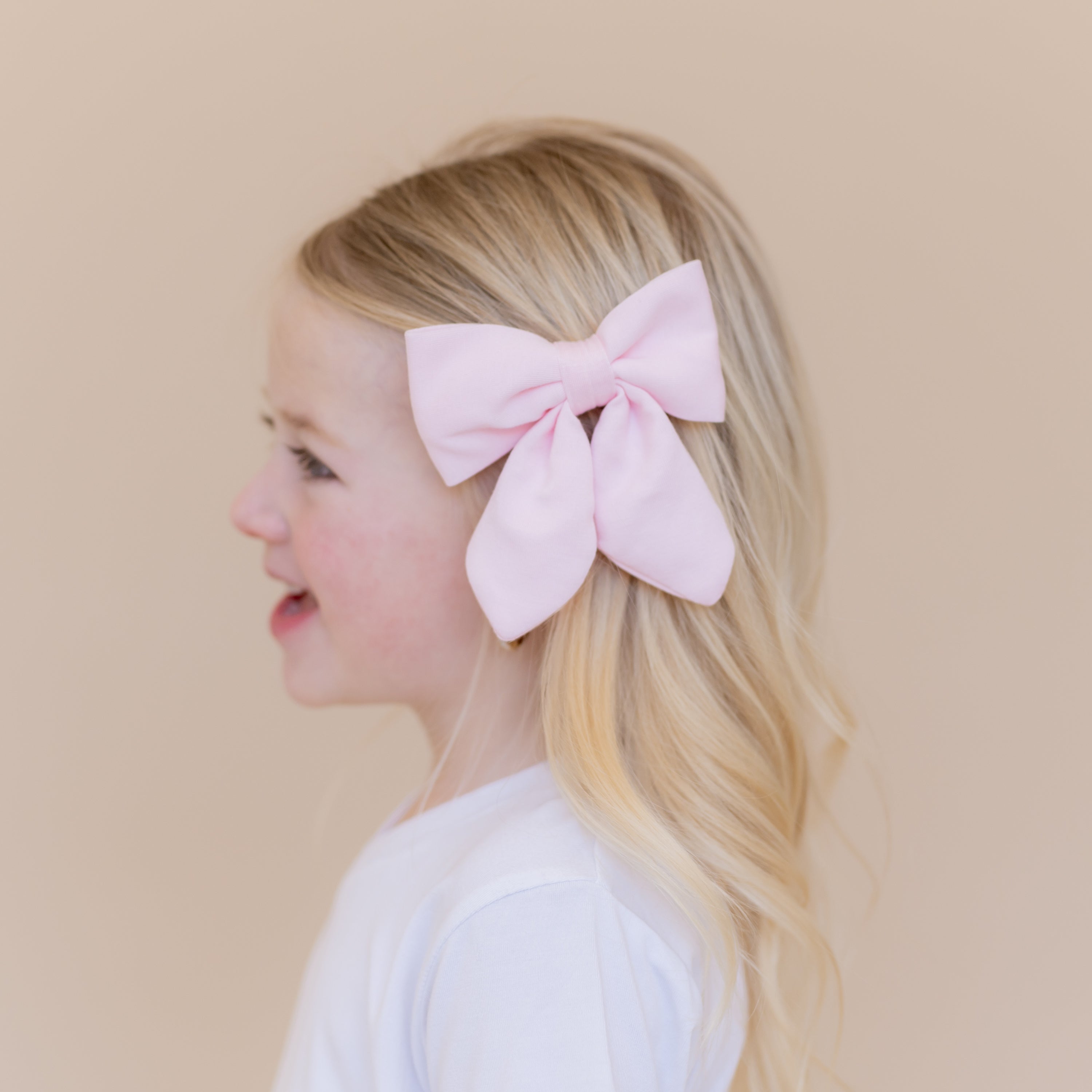Medium Alligator Clip Bow in Sakura shown in a young girls hair