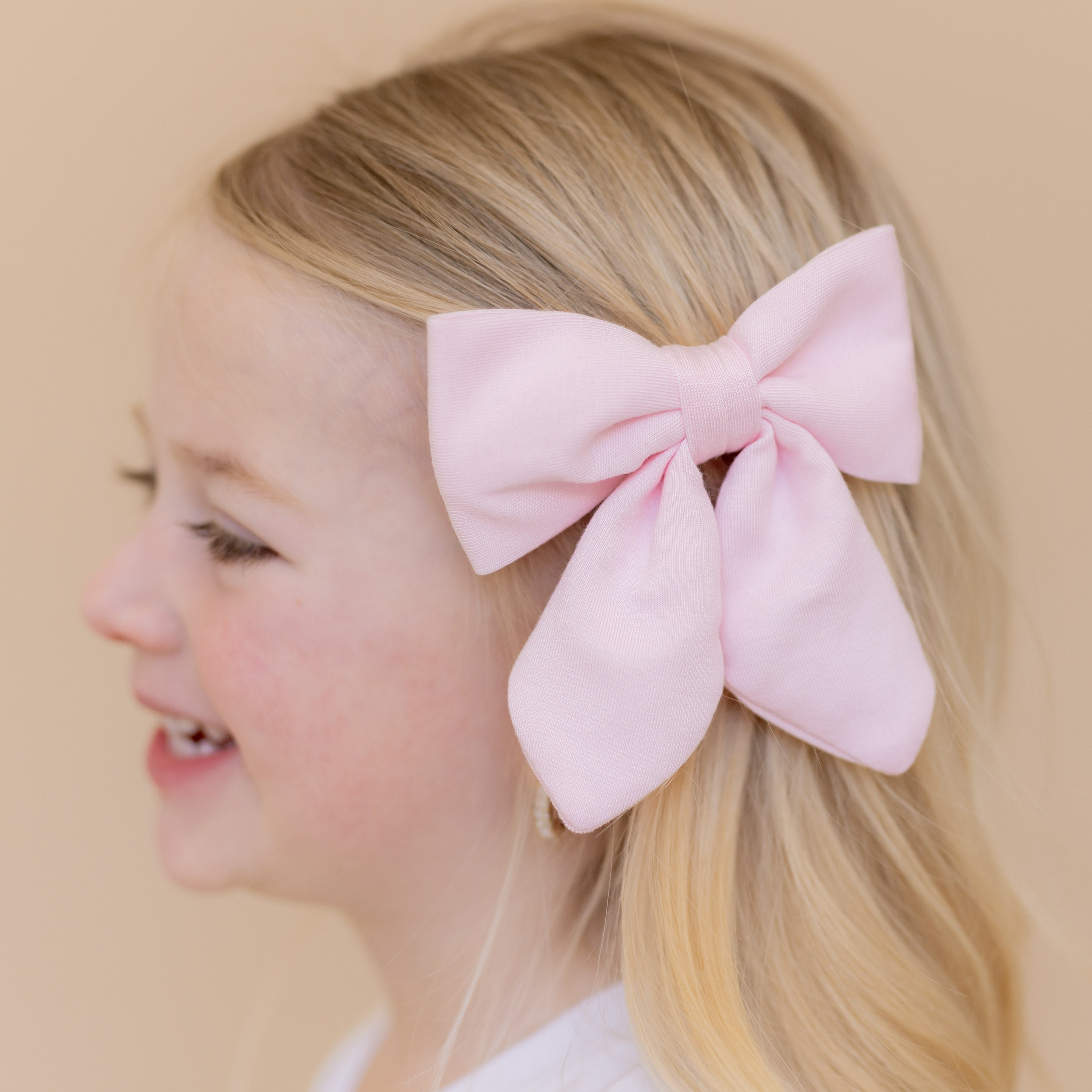 Close up of the Medium Alligator Clip Bow in Sakura shown in a young girls hair