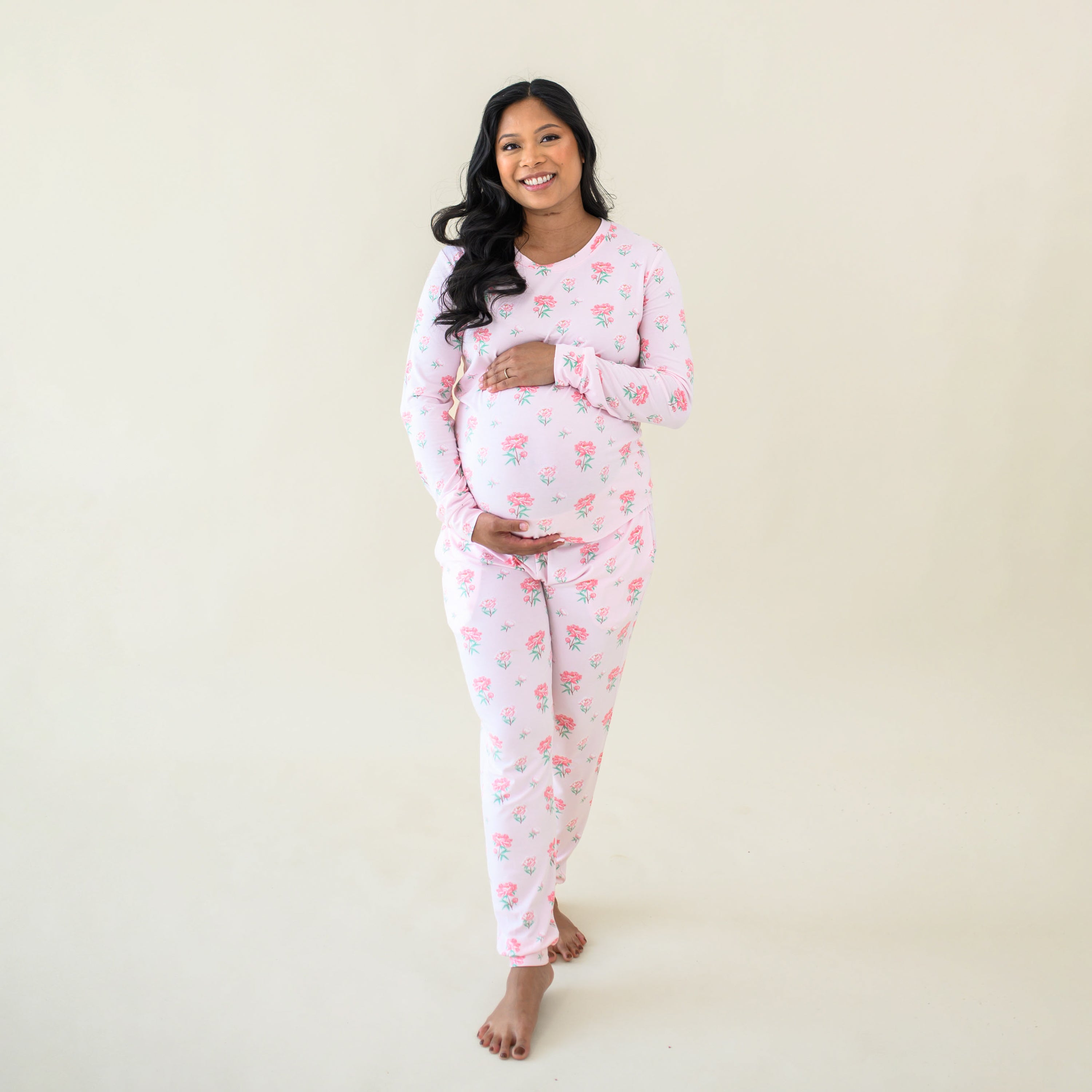 Smiling expectant mother cradling her baby bump wearing the Women's Jogger Pajama Set in Sakura Peony