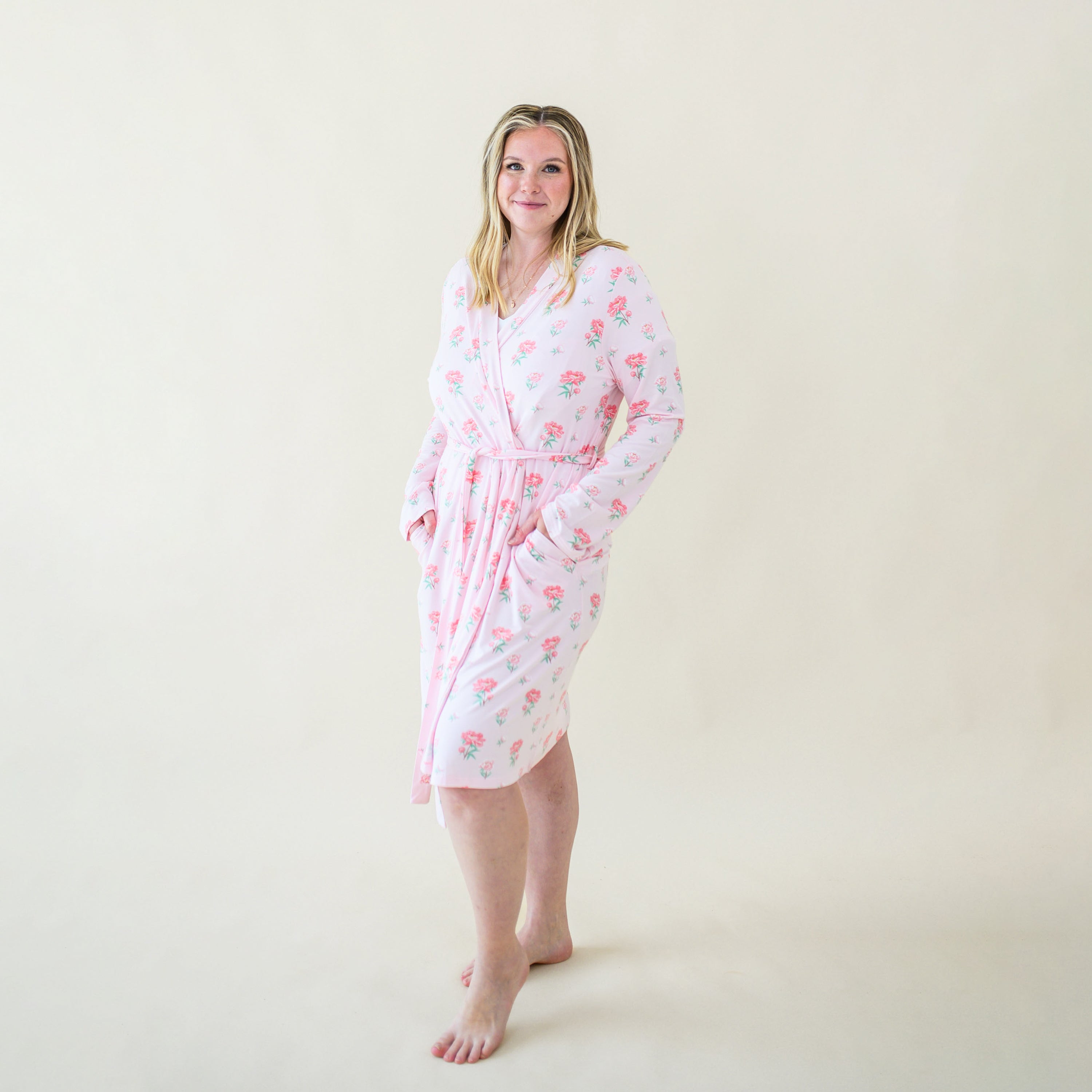 Smiling model wearing the Women's Lounge Robe in Sakura Peony tied up with both hands in the pockets