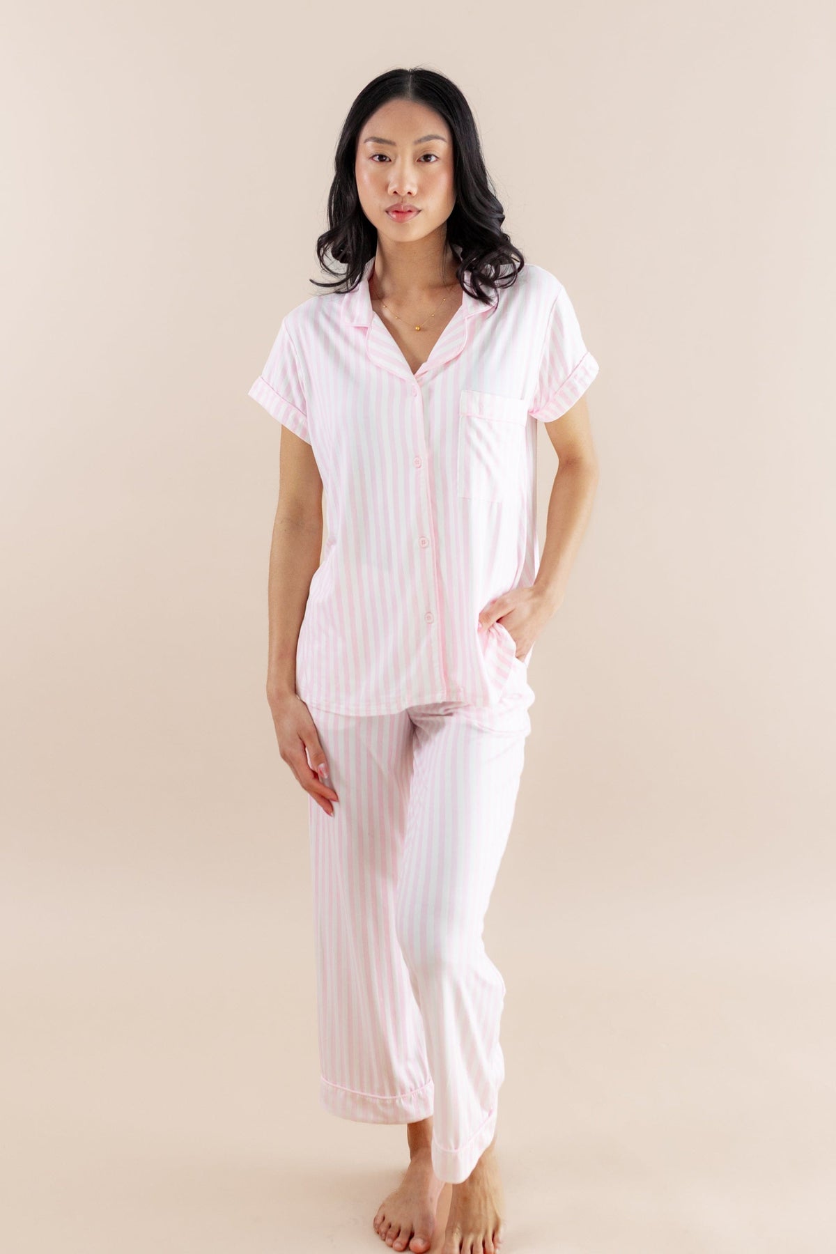 Woman wearing a pink striped pajama set against a beige background