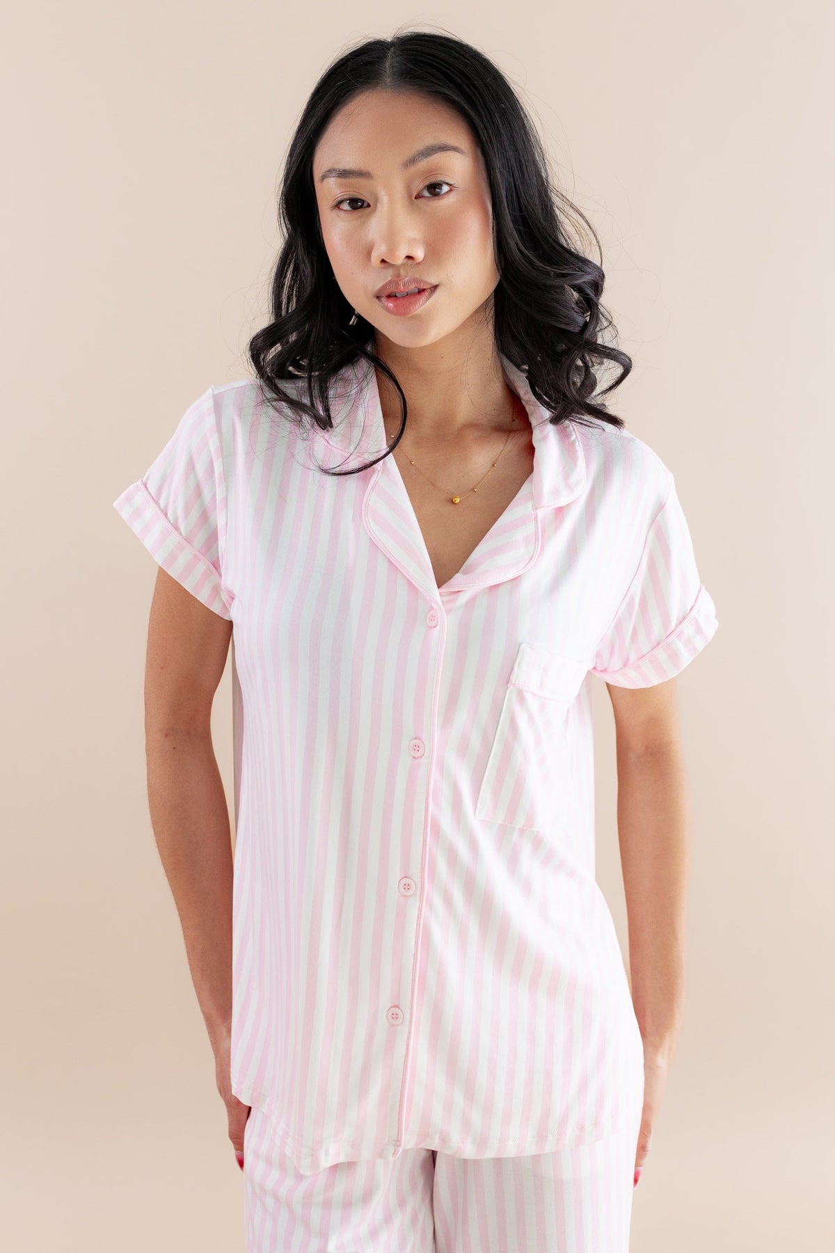 Woman wearing a pink striped pajama set against a beige background