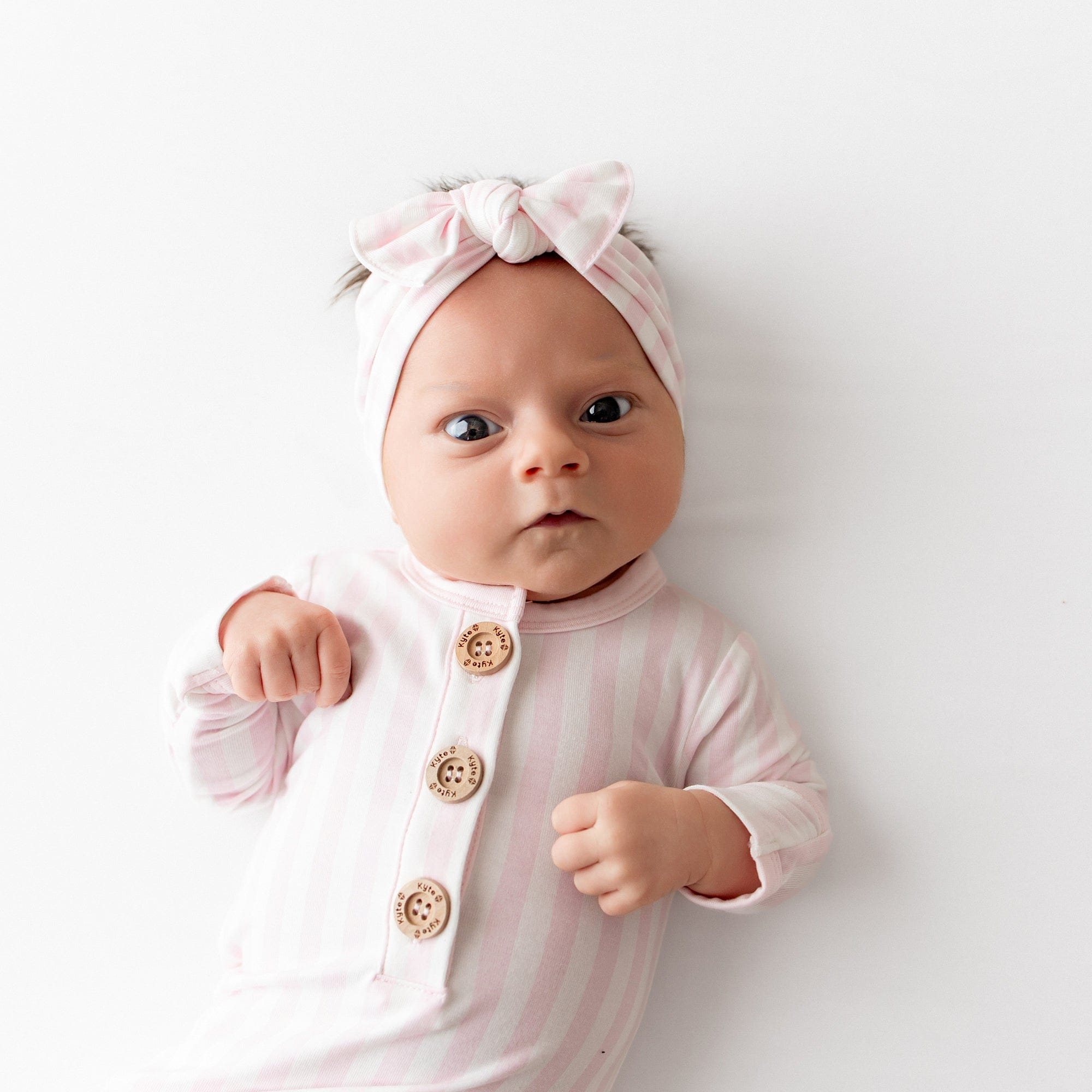 Close up of a newborn wearing the Knotted Gown with Bow Set in Small Sakura Stripe
