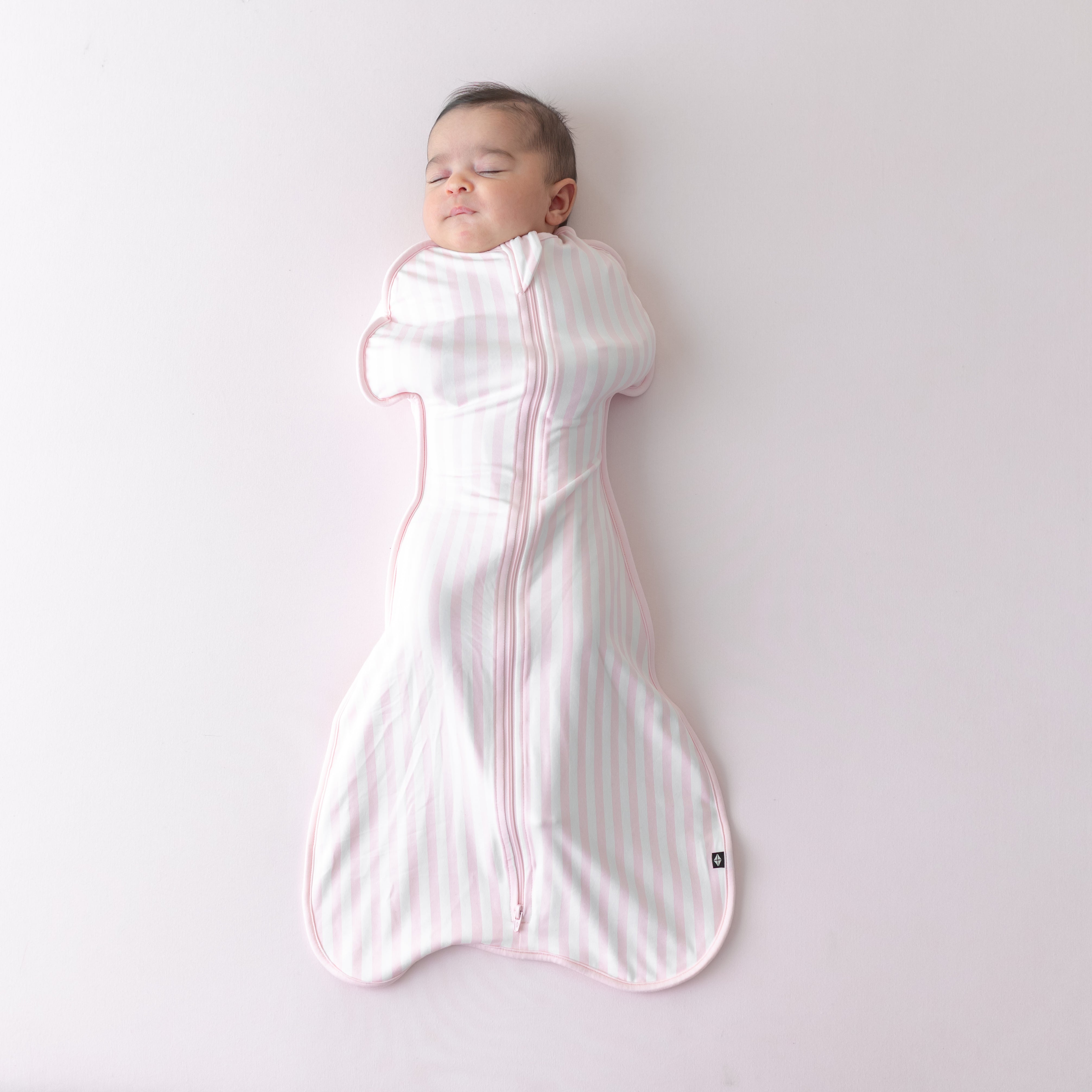 Sleeping newborn wearing the soft and stretchy Swaddle Bag in Small Sakura Stripe 0.5