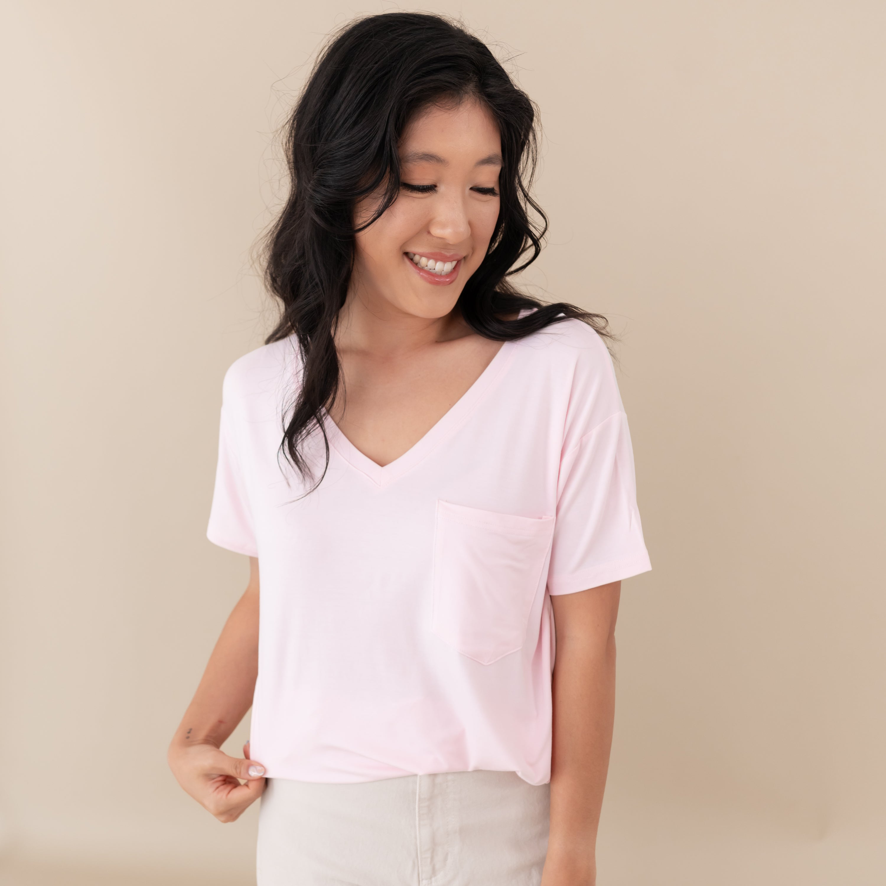 Woman modeling Women’s Relaxed Fit V-Neck in Sakura against a tan backdrop