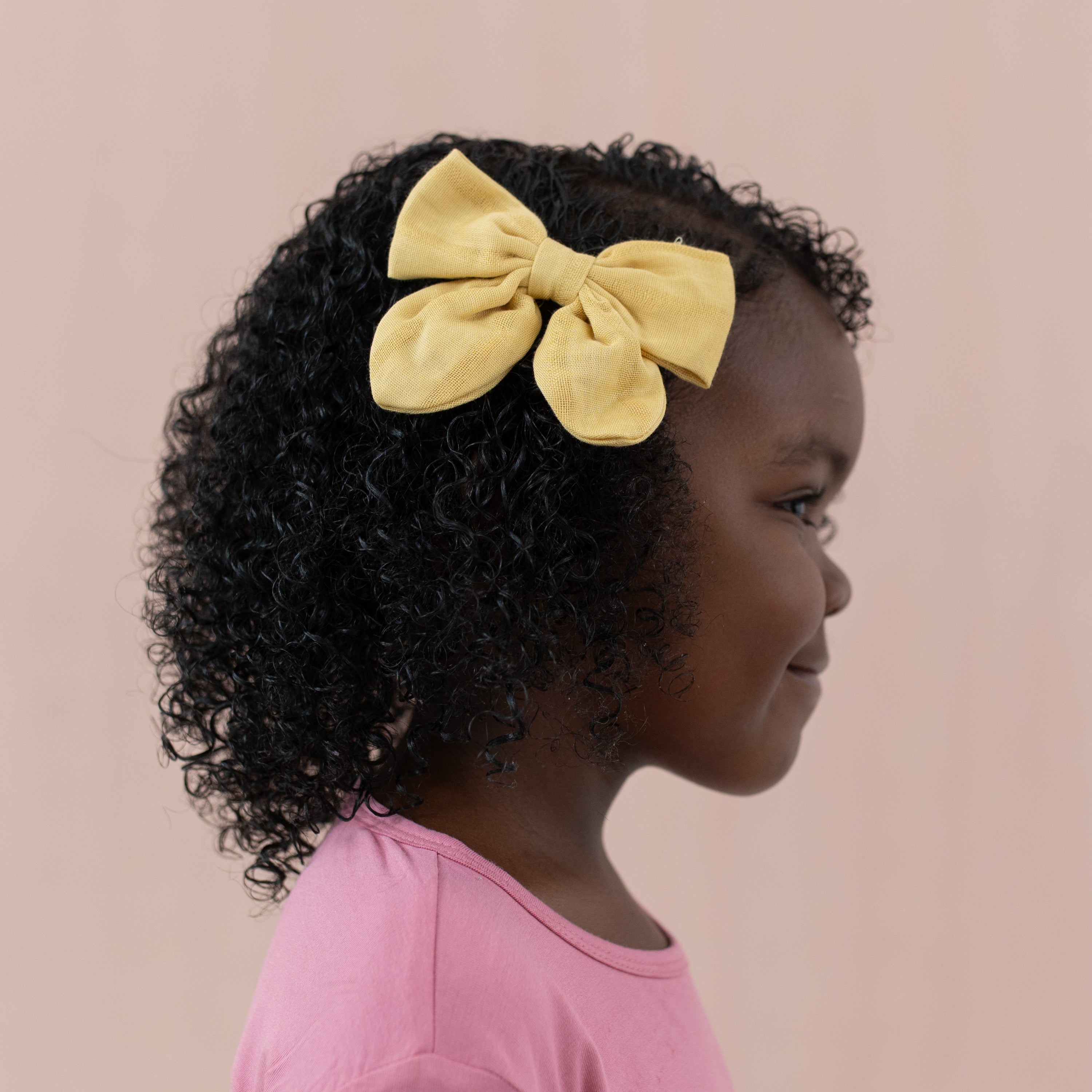 Girl wearing Bamboo Muslin Alligator Clip Bow in Sandcastle Yellow