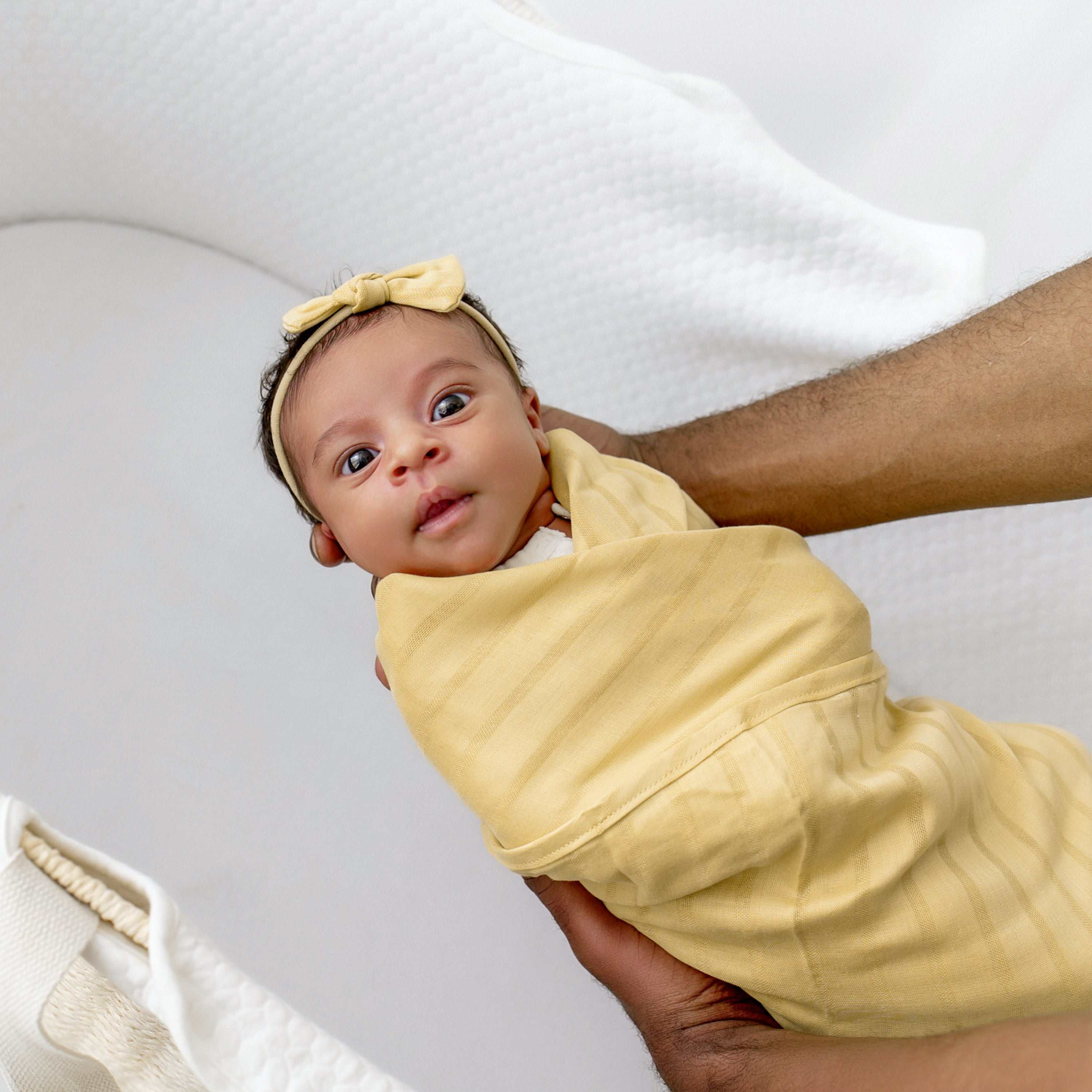 Newborn wrapped in Bamboo Muslin Swaddle Blanket in Sandcastle Yellow with Matching Bow