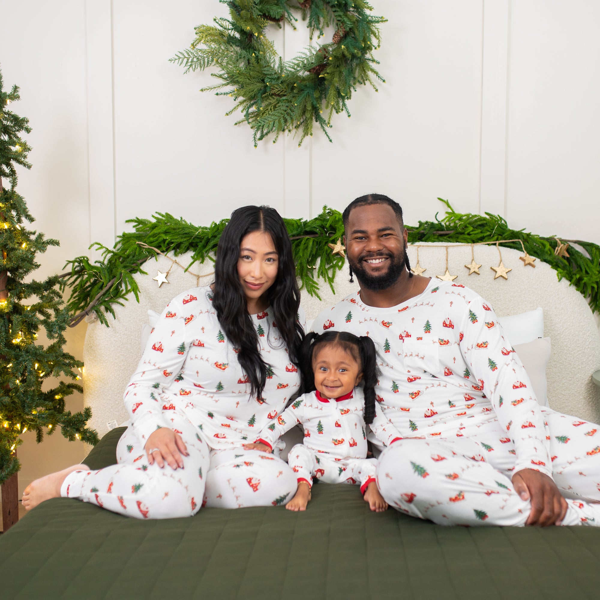 Family of three sitting on a bed matching in Santa Sleigh