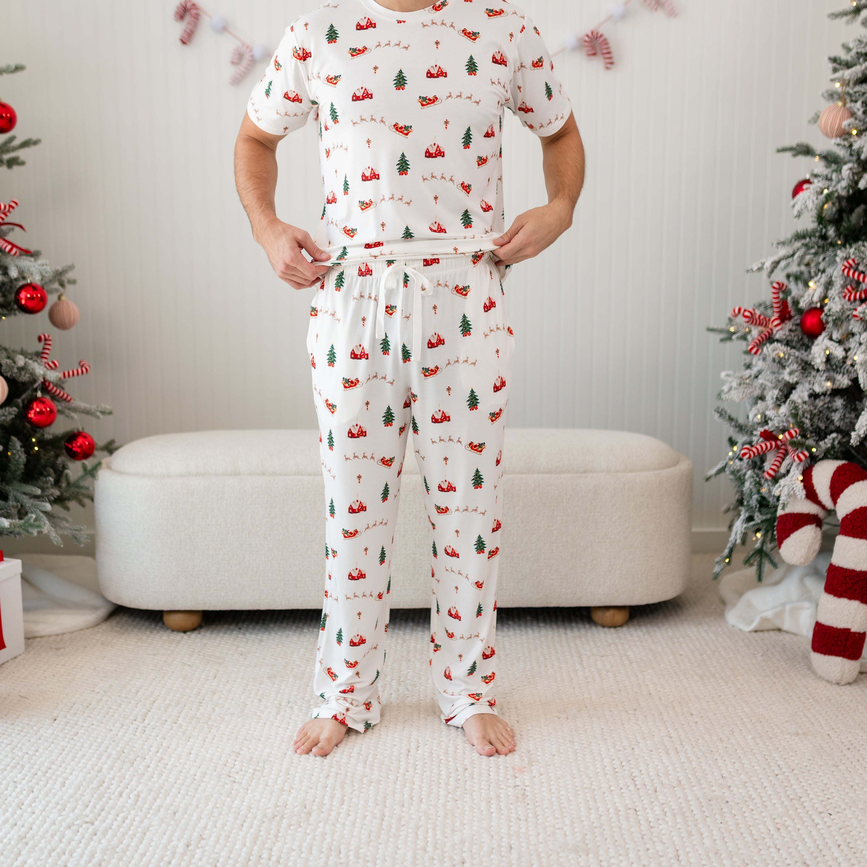 Men's Lounge Pants in Santa Sleigh shown on a male model who is standing in front of Christmas decor