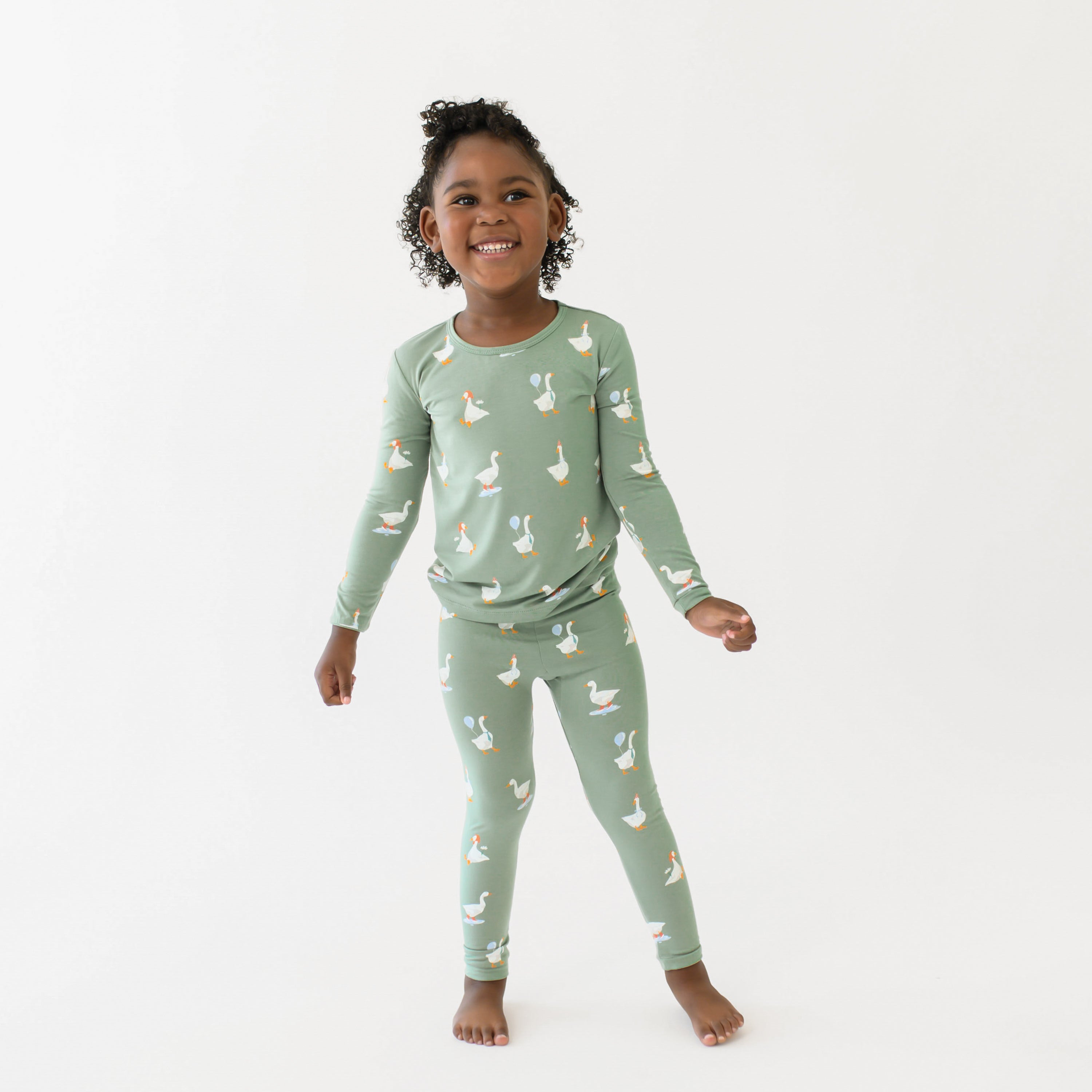 smiling girl standing with her arms out wearing the Long Sleeve Pajamas in Silly Goose in front of a white backdrop