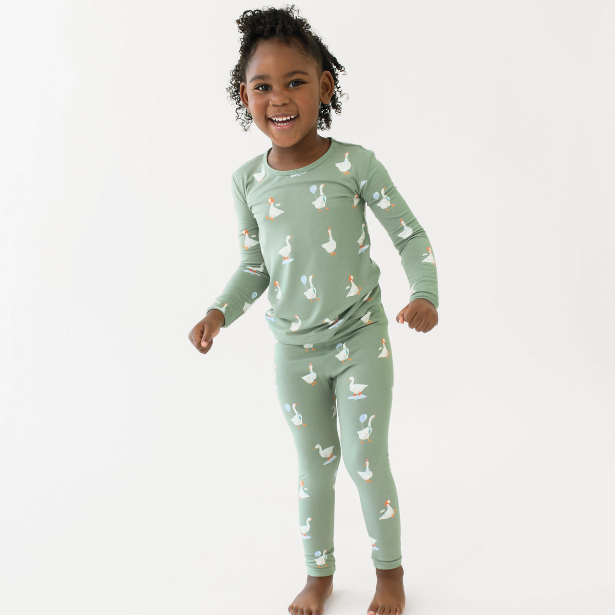Young girl smiling wearing the Long Sleeve Pajamas in Silly Goose in front of a white backdrop