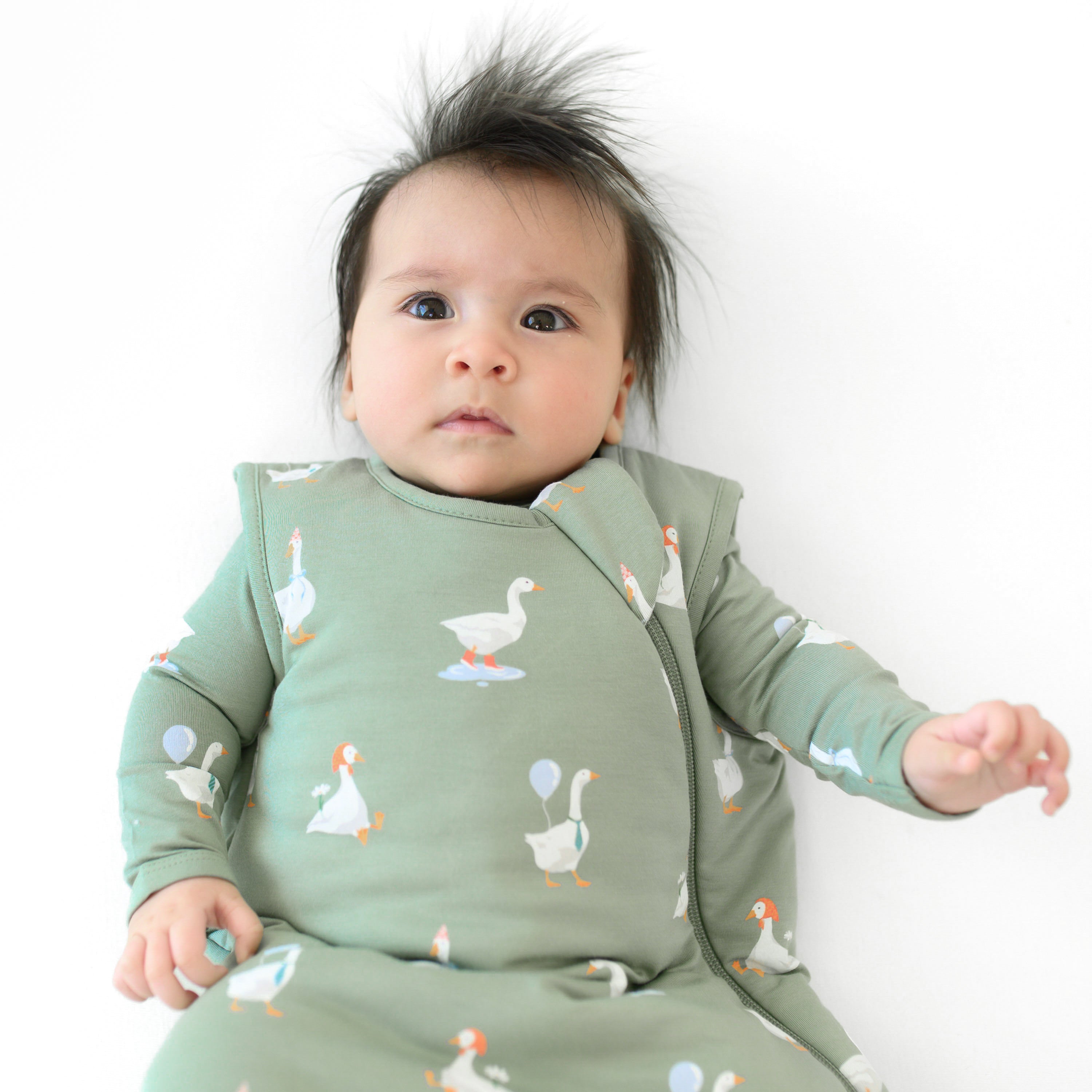 Infant wearing the Sleep Bag in Silly Goose 1.0 with matching green pajamas