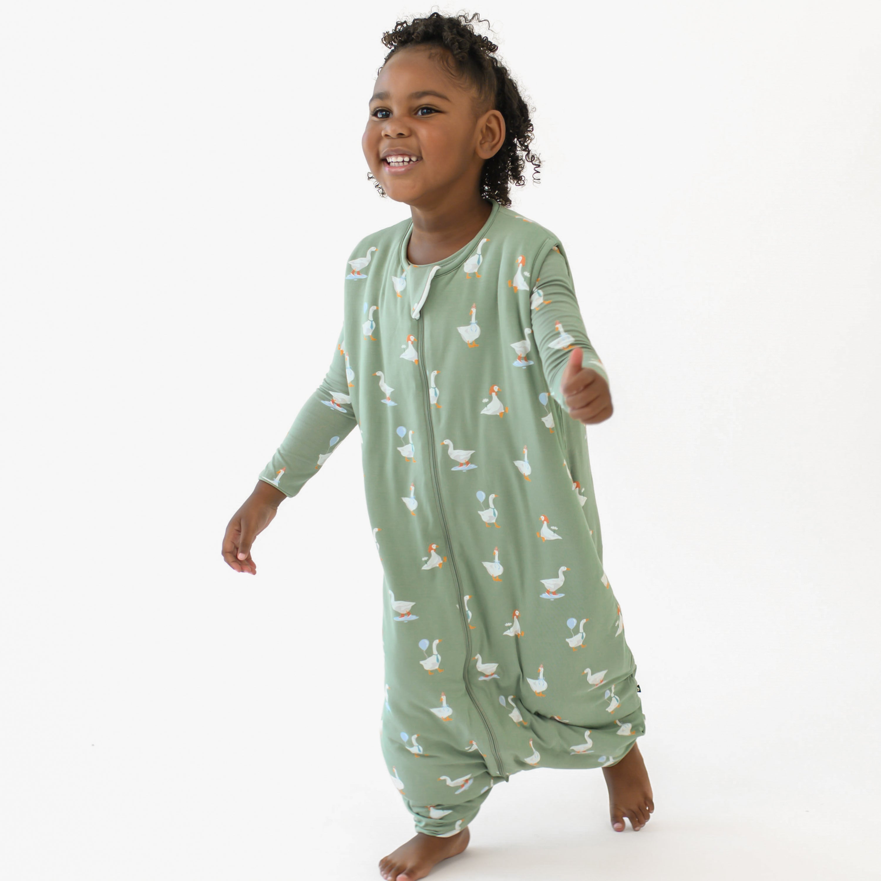 Young girl walking wearing the Sleep Bag Walker in Silly Goose 1.0 with matching long sleeve pajama bottoms on underneath