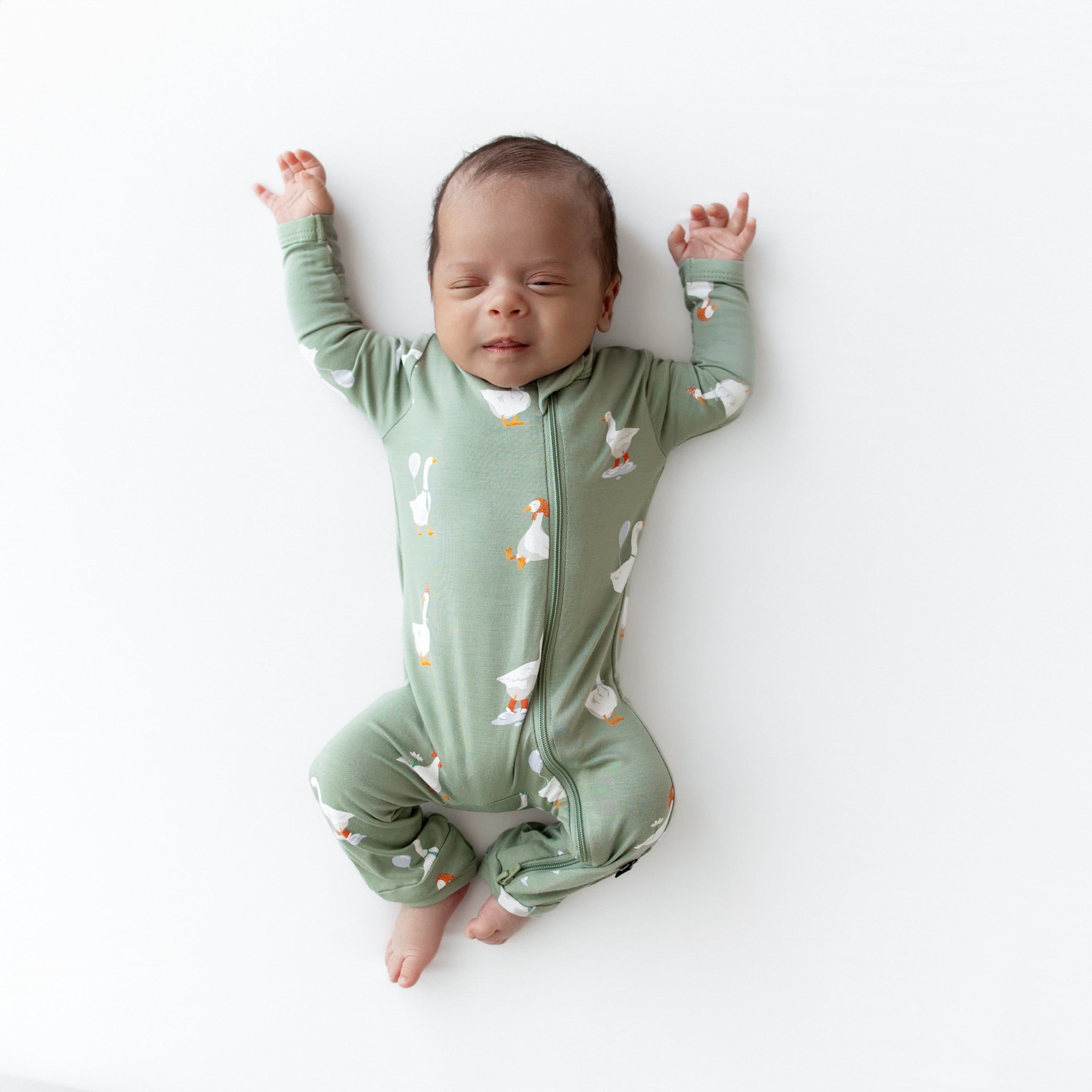 Sleeping newborn laying stretched out wearing thhe Zippered Romper in Silly Goose