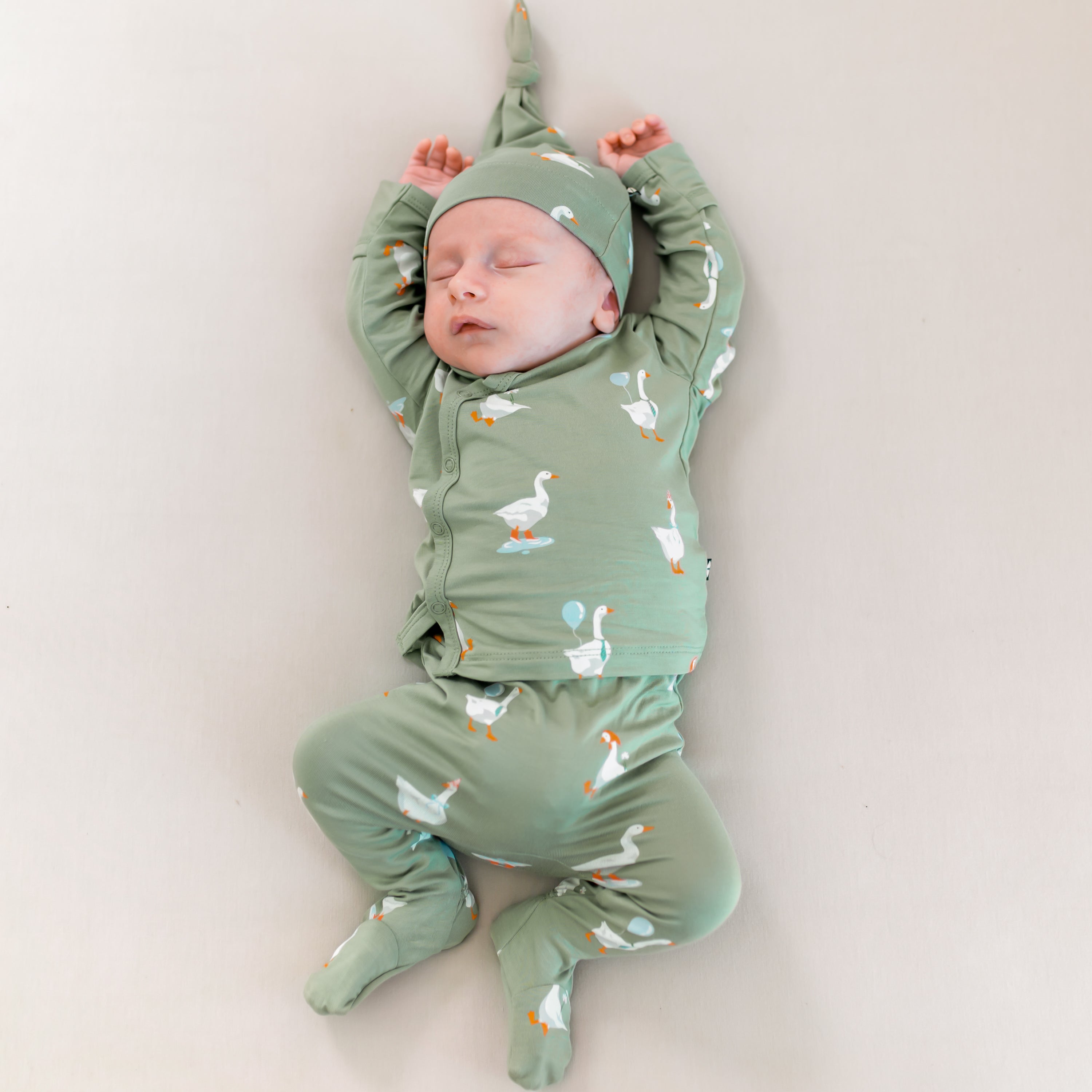 Sleeping newborn laying down with arms above their head wearing the Take Me Home Set in Silly Goose