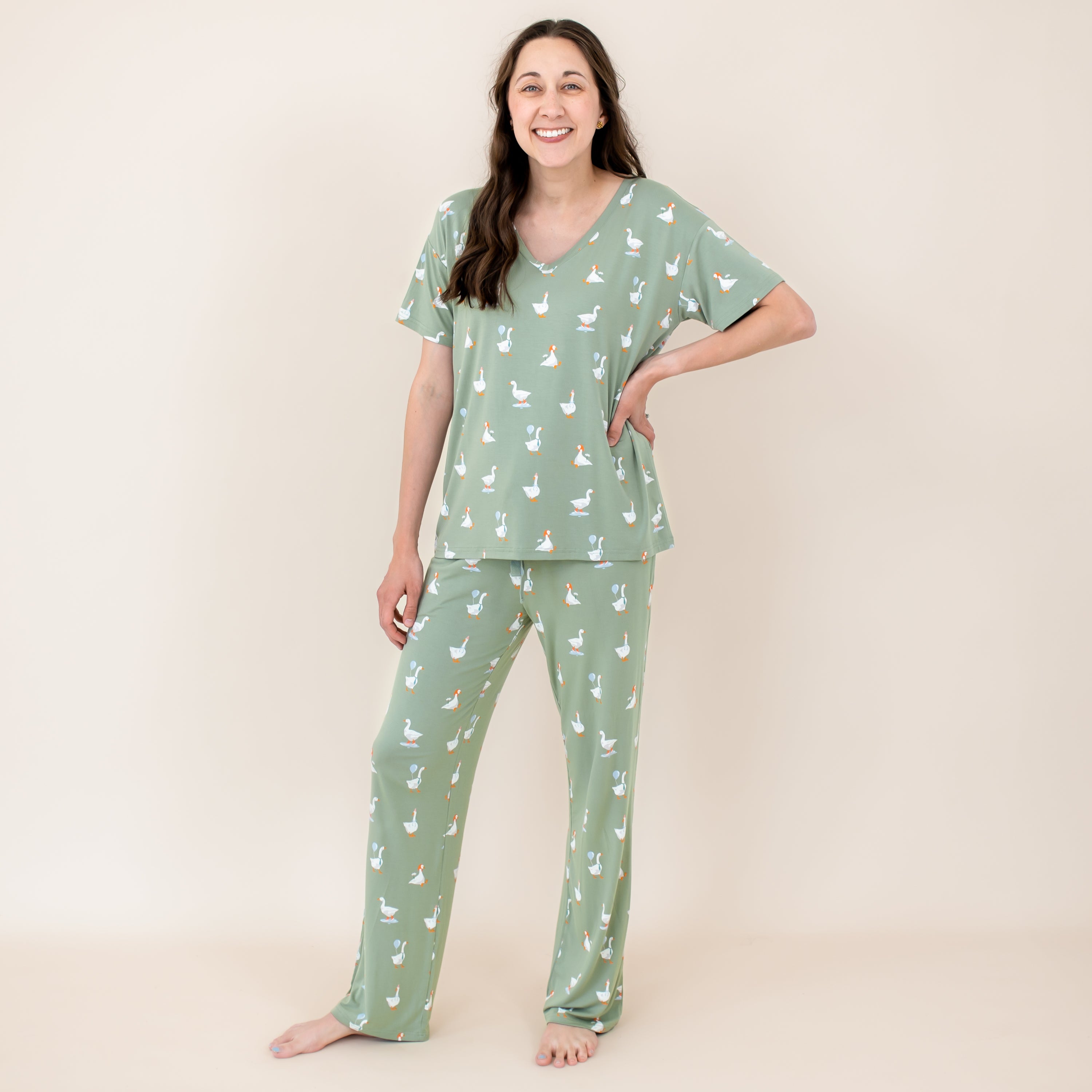 Female model standing with her hand on her hip wearing the Women's Lounge Pants in Silly Goose and matching women's v-neck in front of a light neutral background