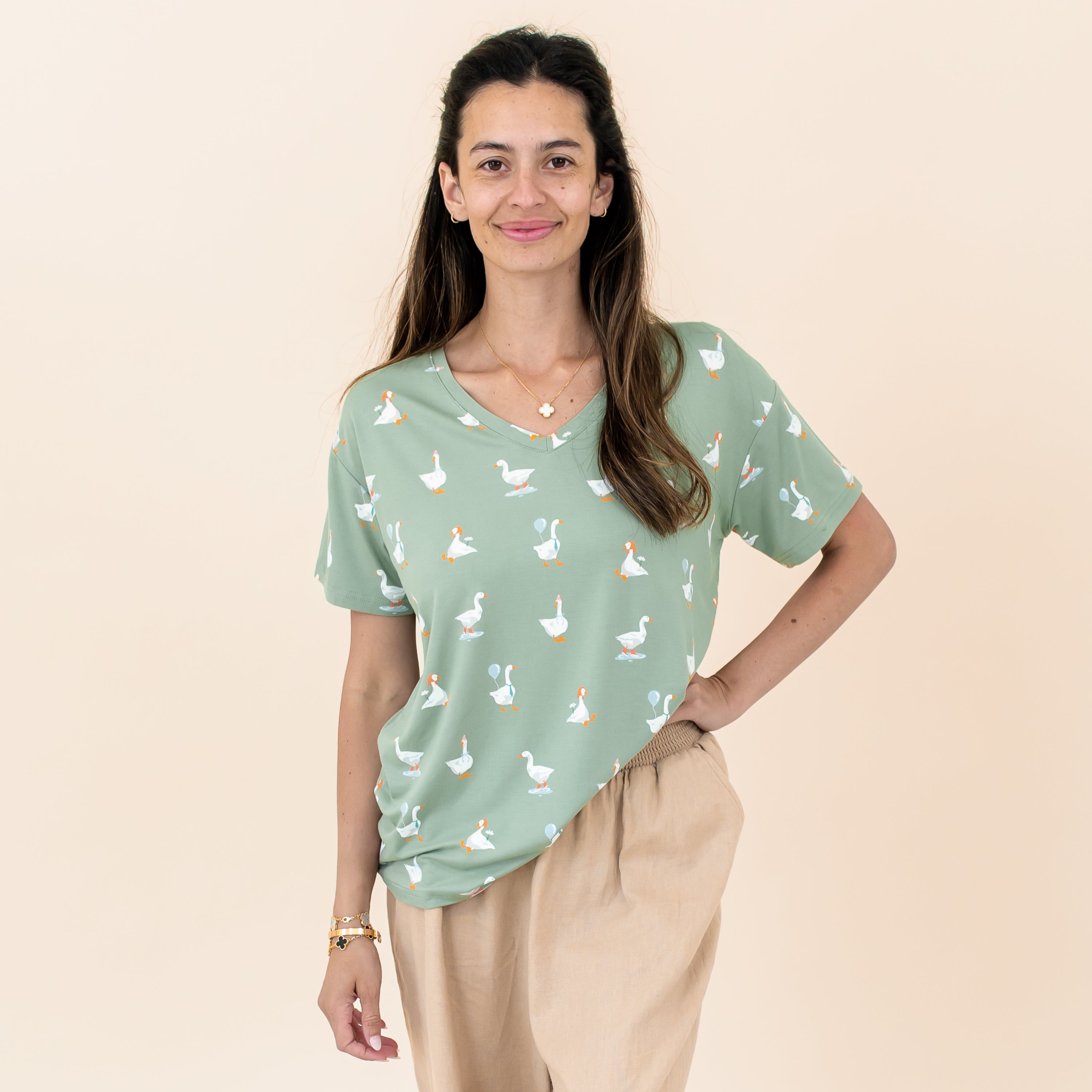 Smiling female model standing with one hand on her hip wearing the Women's Relaxed Fit V-Neck in Silly Goose paired with khaki colored pants