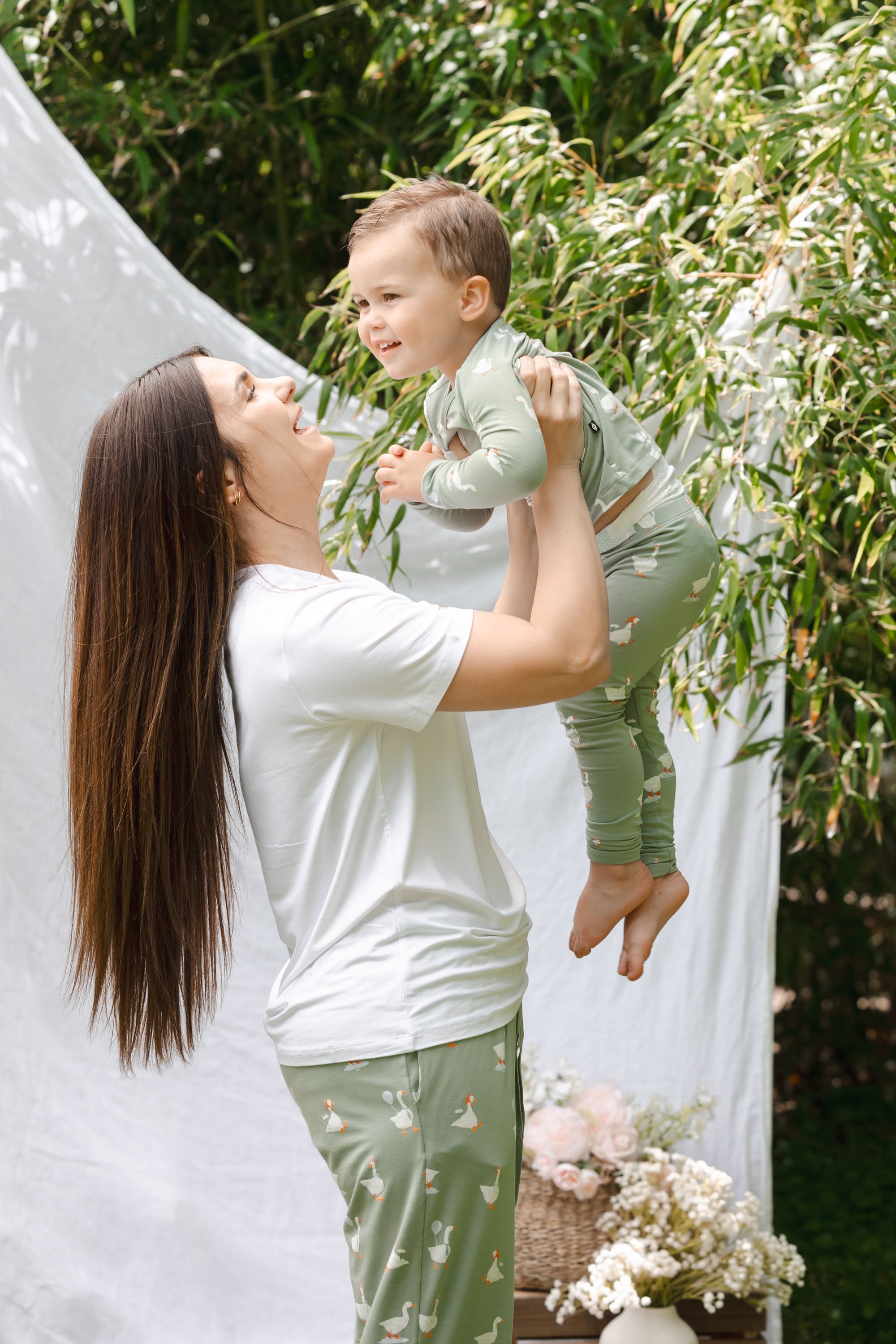 Mom holding up toddler wearing silly goose pajamas outdoors