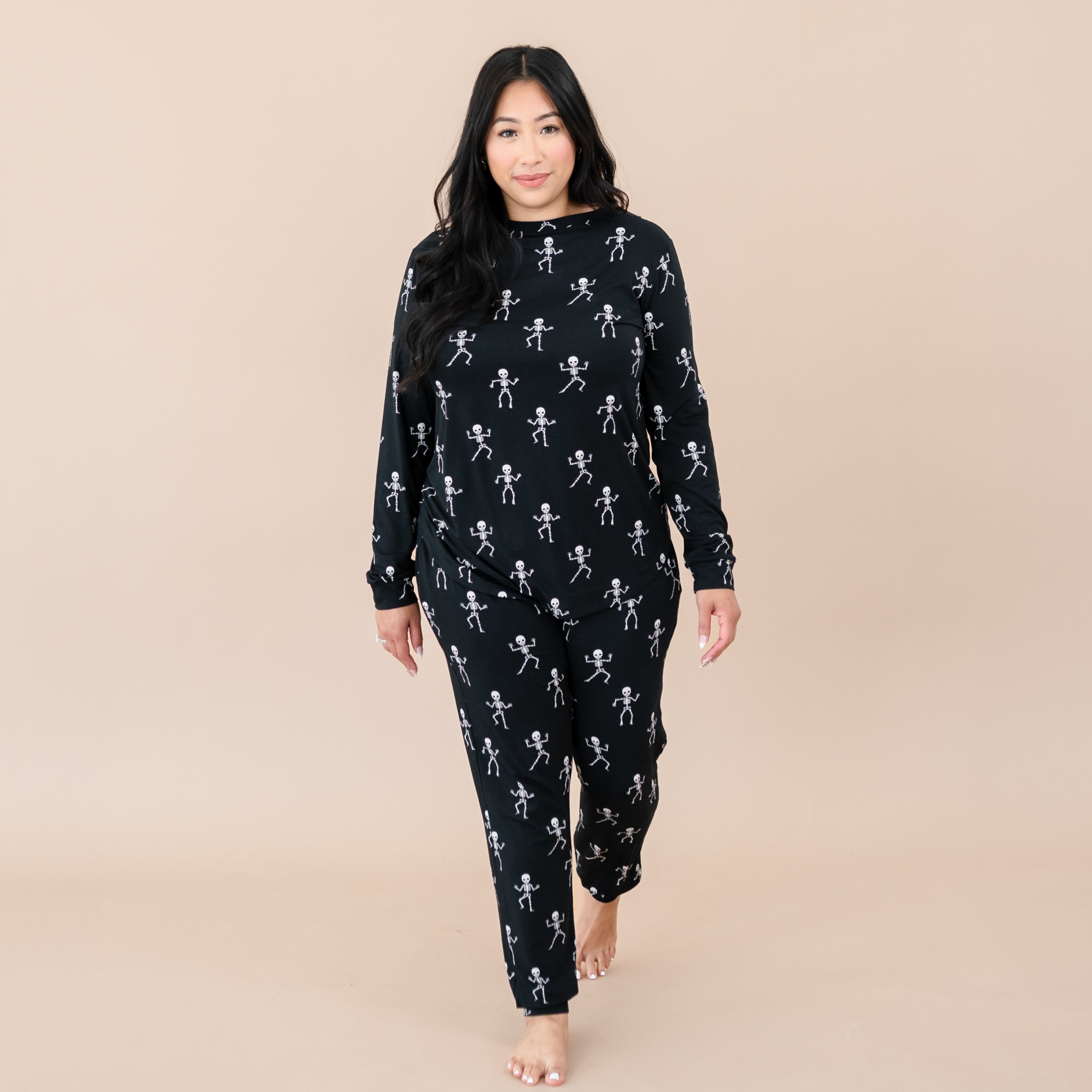Female model walking wearing the Women's Jogger Pajama Set in Skeleton in front of a light beige backdrop