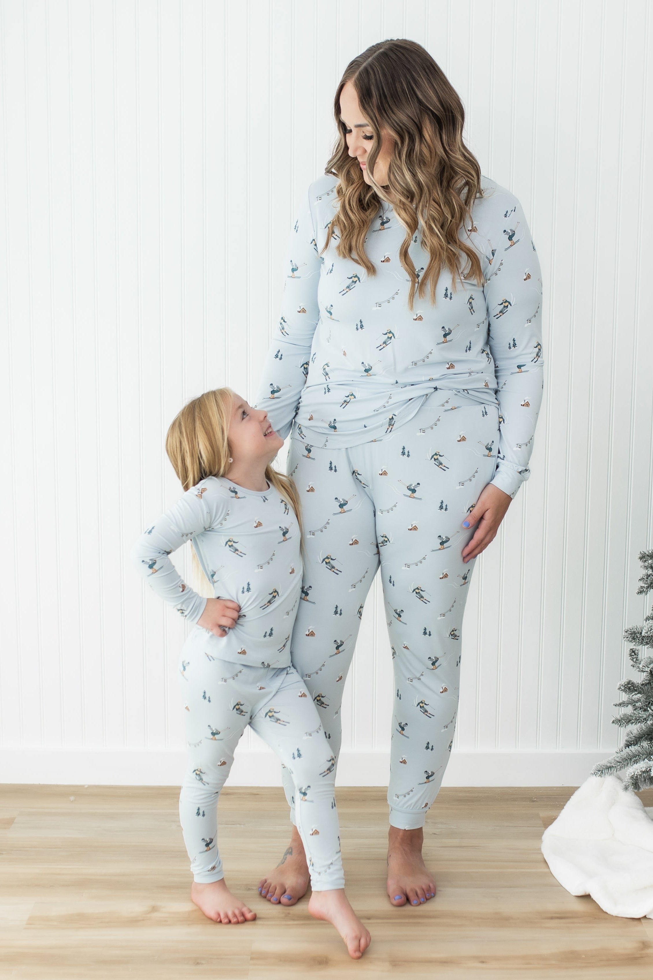 Mother and daughter standing side by side both looking at one another matching in Women's Jogger Pajama Set in Ski and toddler pajamas