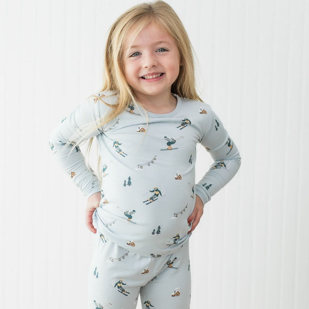 Young girl wearing Kyte Baby bamboo long sleeve pajamas with a ski print