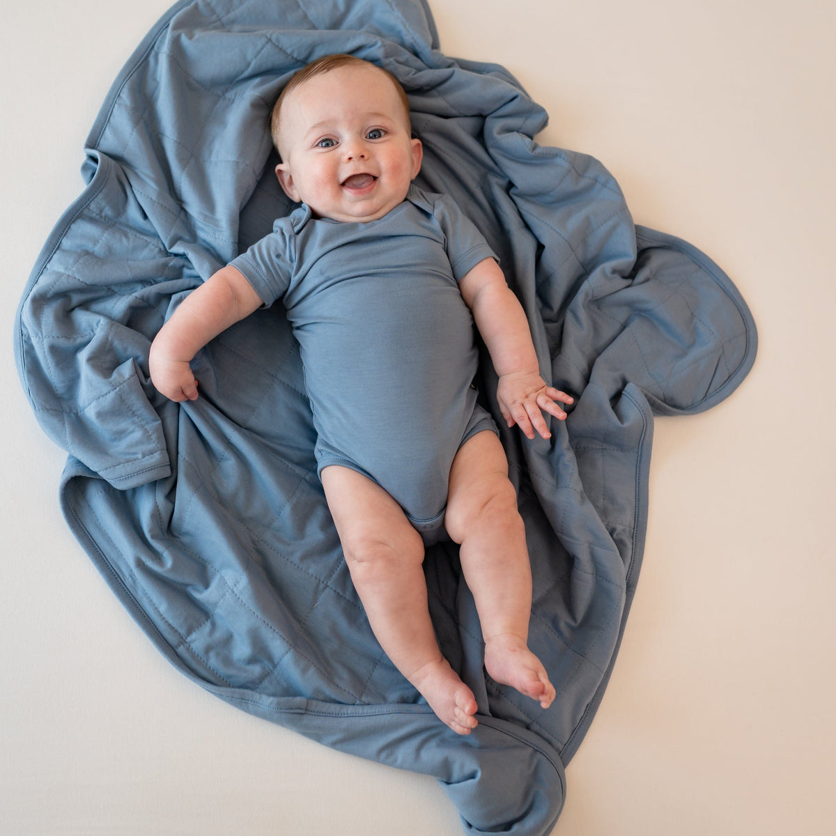 Baby in Slate Bodysuit laying on Baby Blanket in Slate 1.0