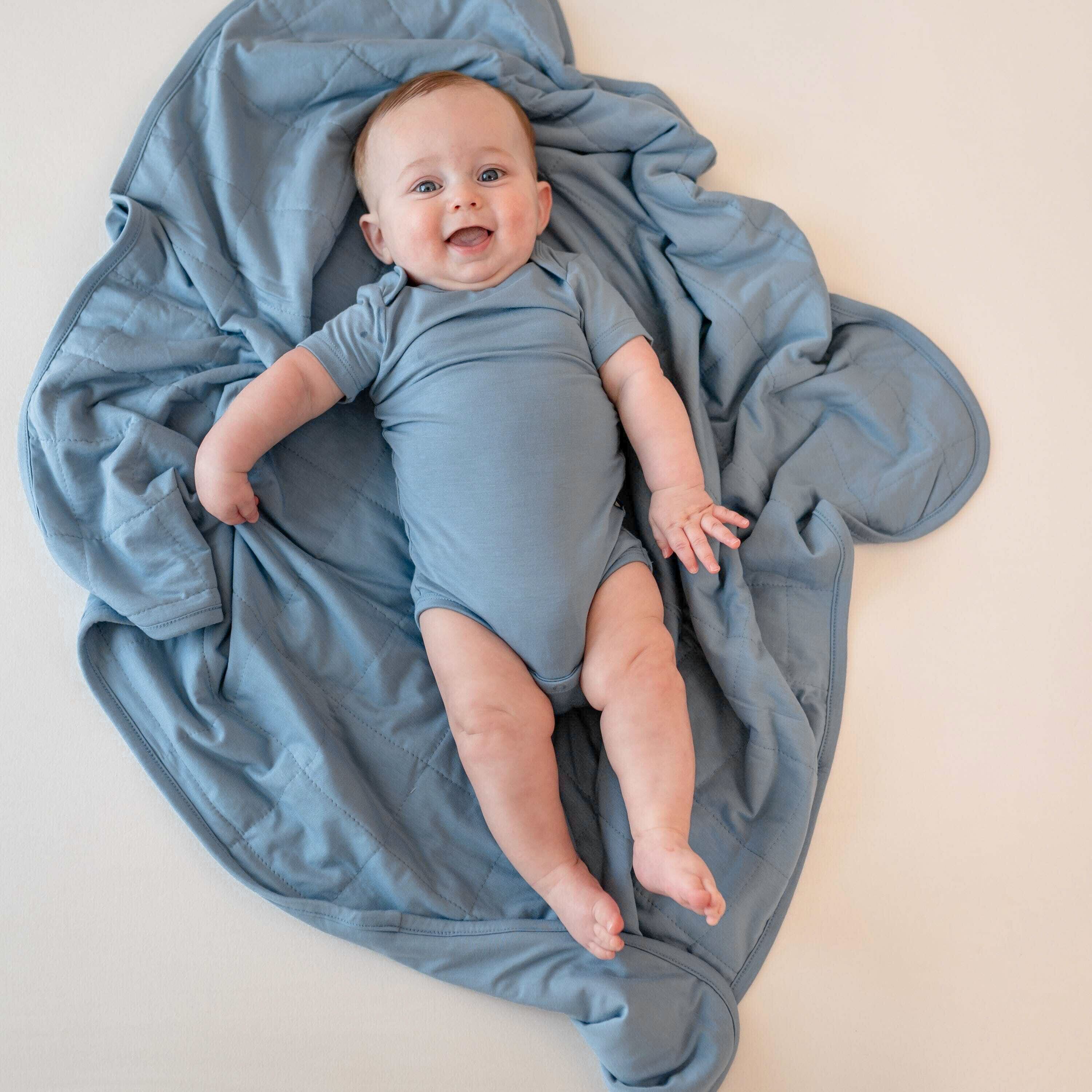 Baby in a blue bodysuit laying on a blue blanket