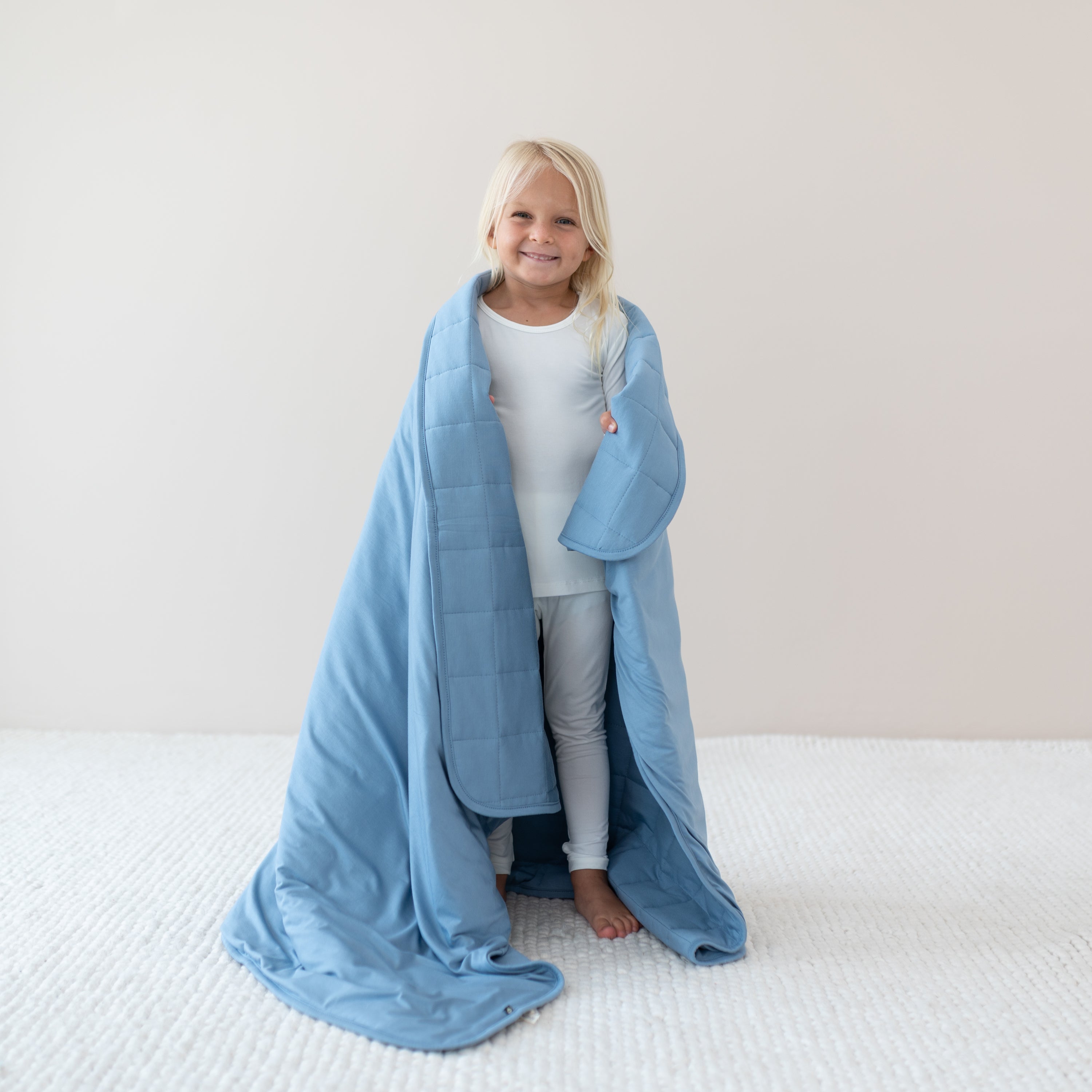 Child wrapped in Youth Blanket in Slate 2.5 wearing cloud long sleeve pajamas