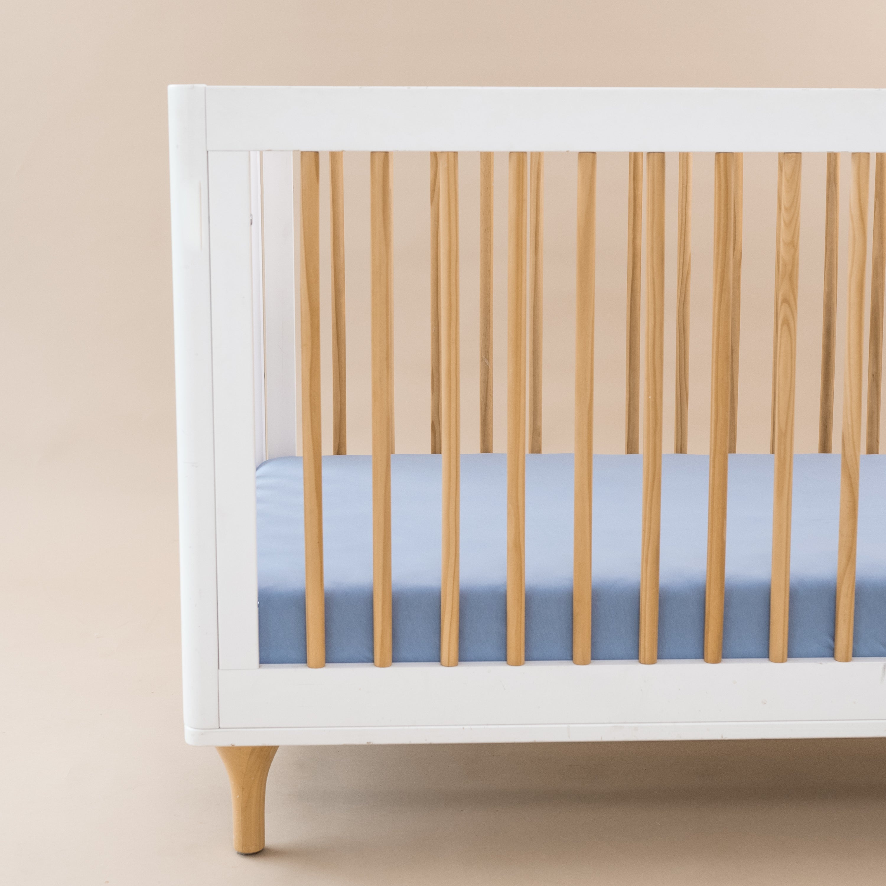 Crib Sheet in Slate shown on a mattress in a modern white and wooden crib