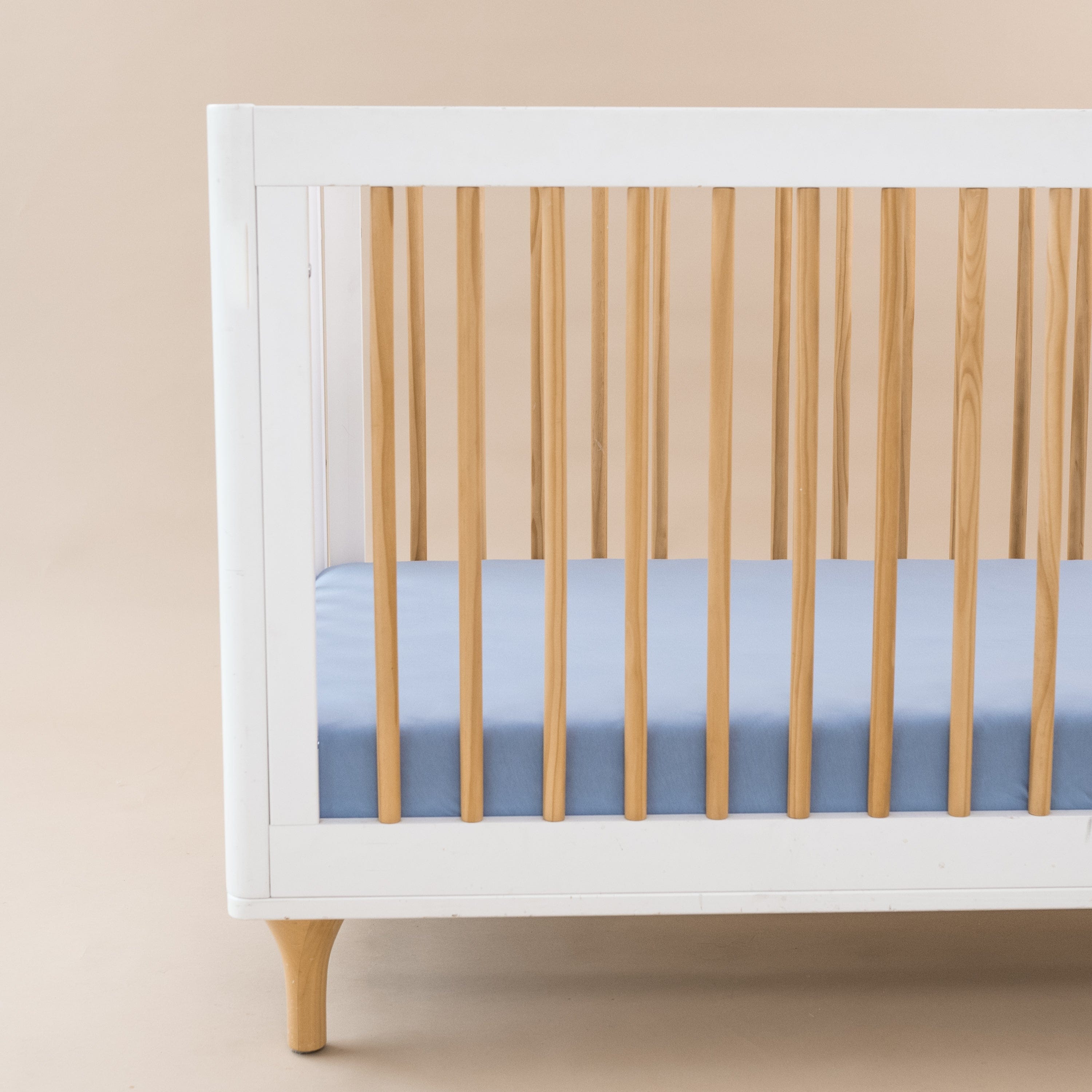 Crib Sheet in Slate shown on a mattress in a modern white and wooden crib