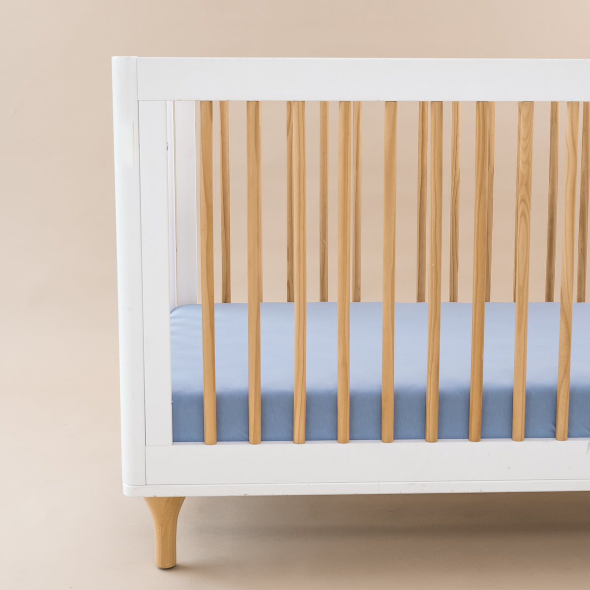 Crib Sheet in Slate shown on a mattress in a modern white and wooden crib
