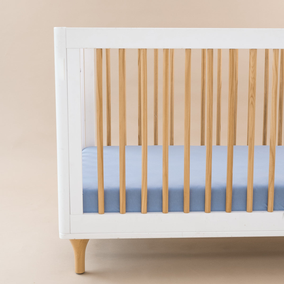 Crib Sheet in Slate shown on a mattress in a modern white and wooden crib