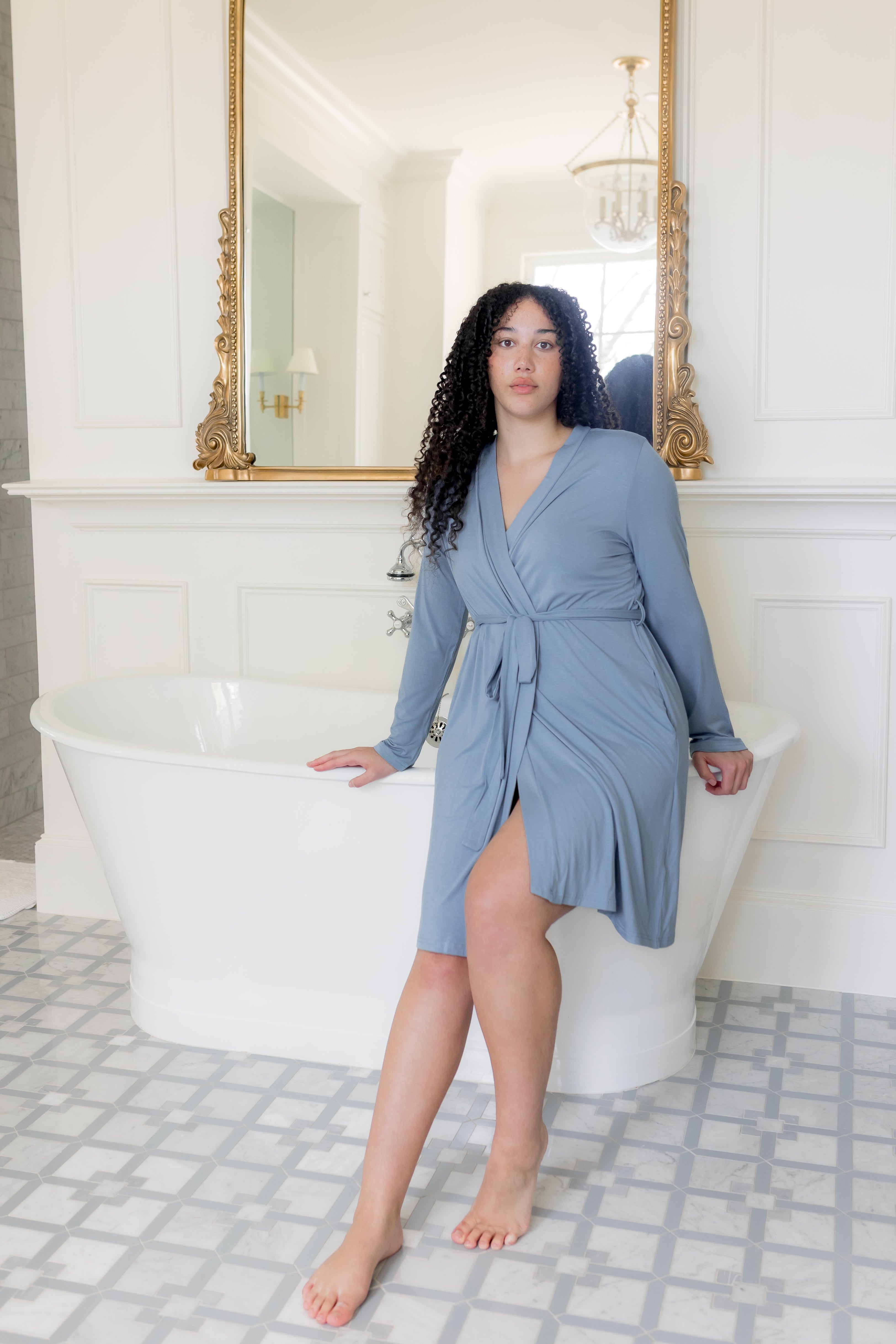 Female sitting on a white tub wearing the Women's Lounge Robe in Slate