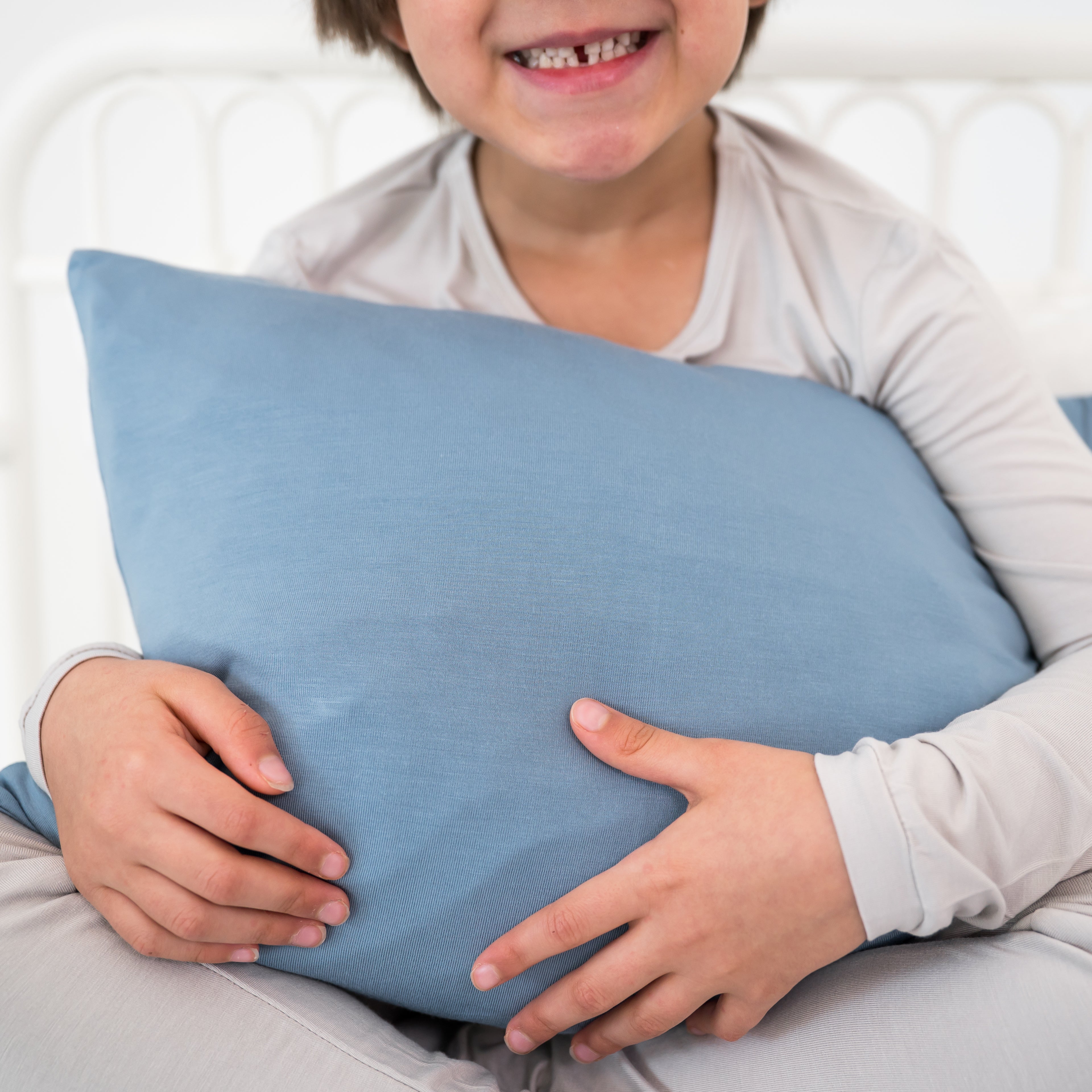 Child holding a blue pillow with a white background