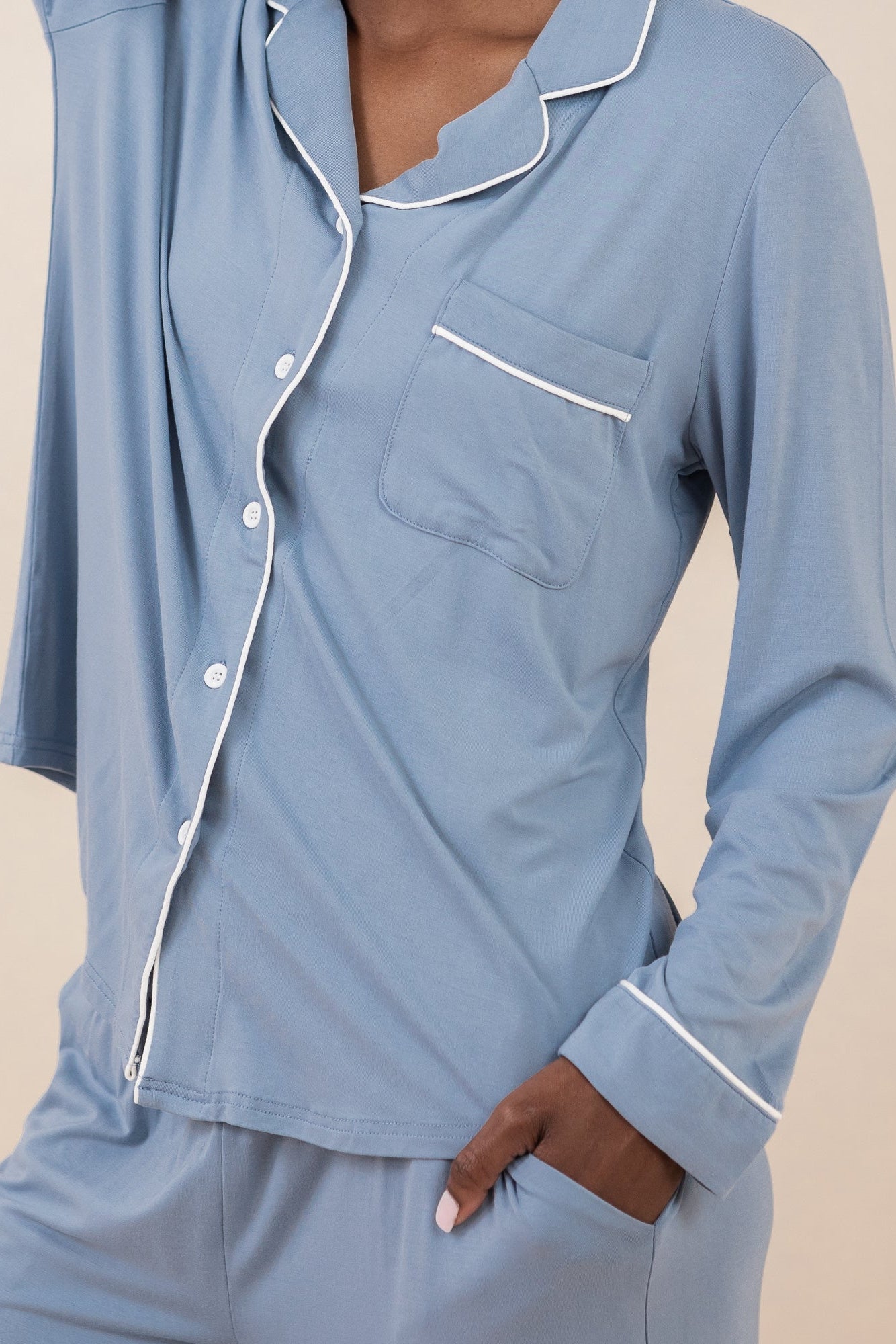 Woman wearing medium blue pajama set with white piping