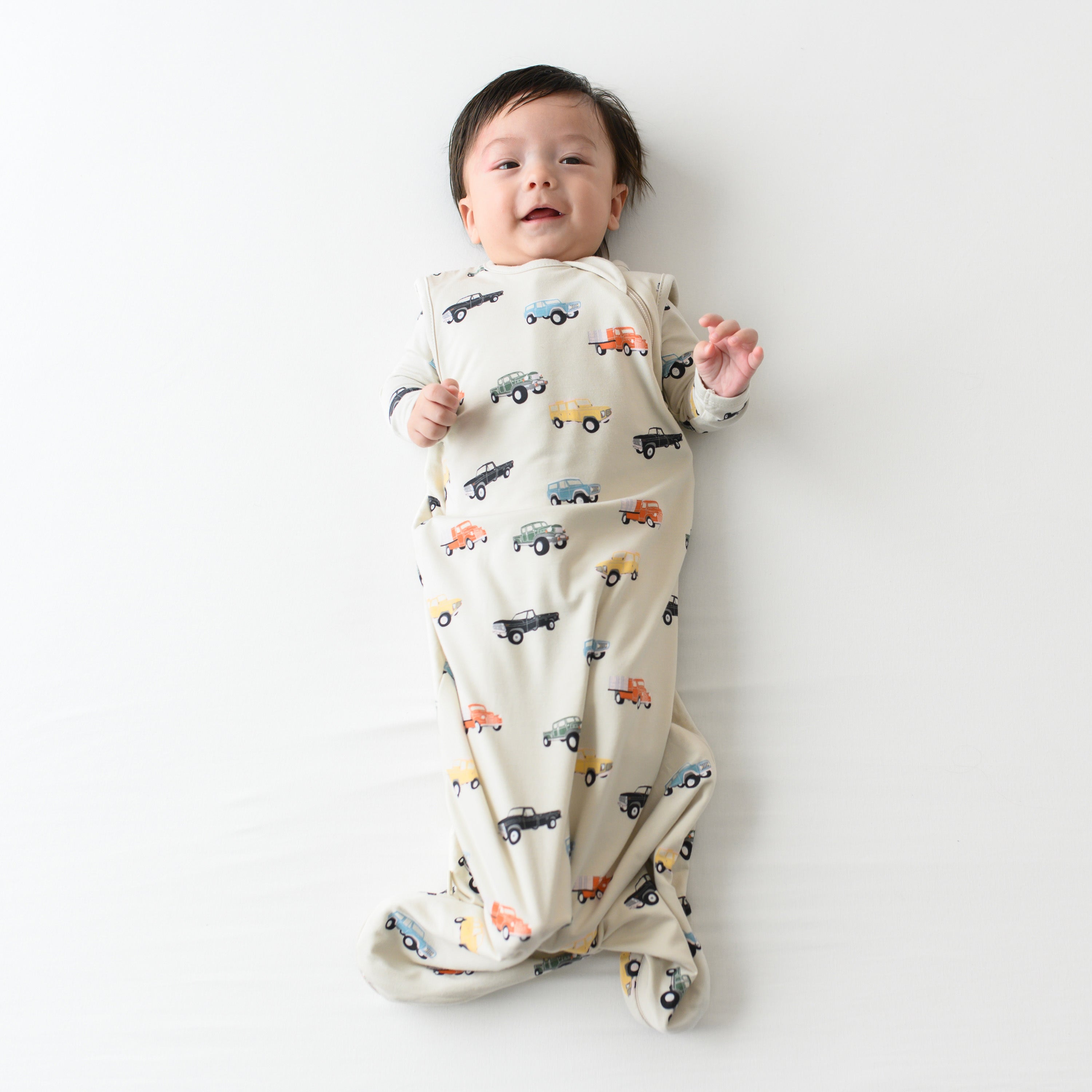 Baby modeling the Sleep Bag in Vintage Truck 0.5 wearing a long sleeve Vintage Truck romper underneath