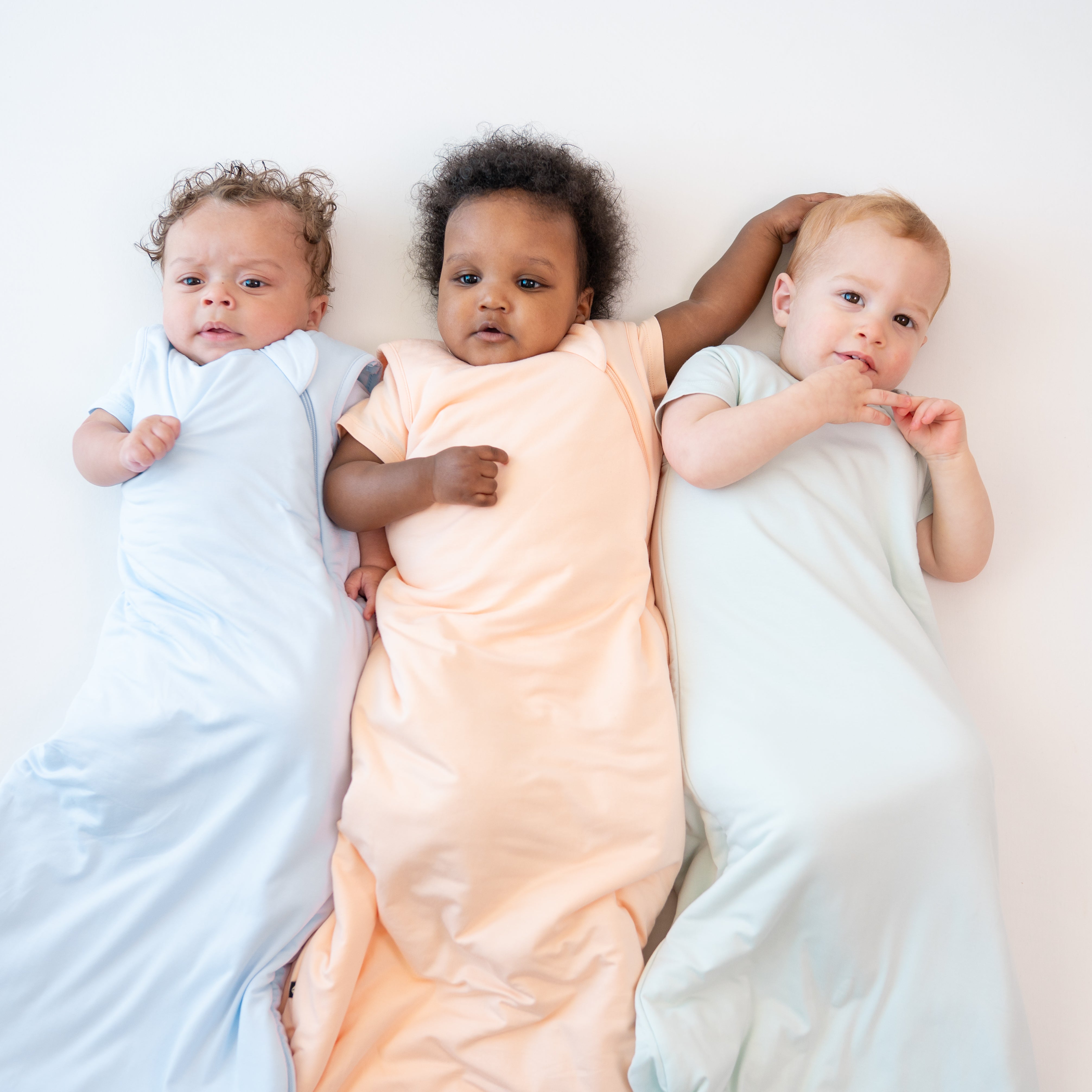 3 infant models wearing 1.0 TOG Sleep Bags in the Summer Solids