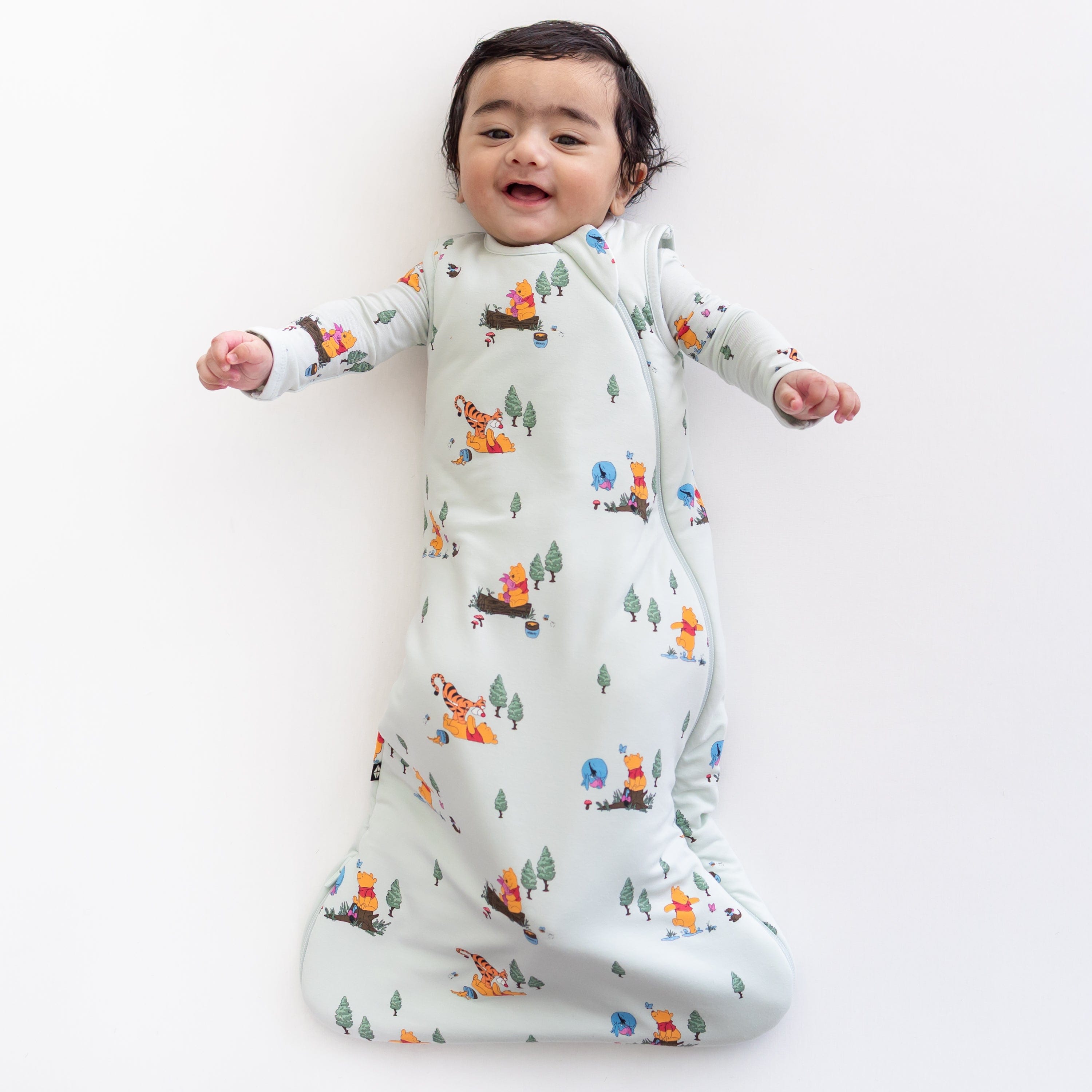 Young infant wearing the Sleep Bag in Winnie the Pooh Hundred Acre Wood 1.0 with a matching romper on underneath