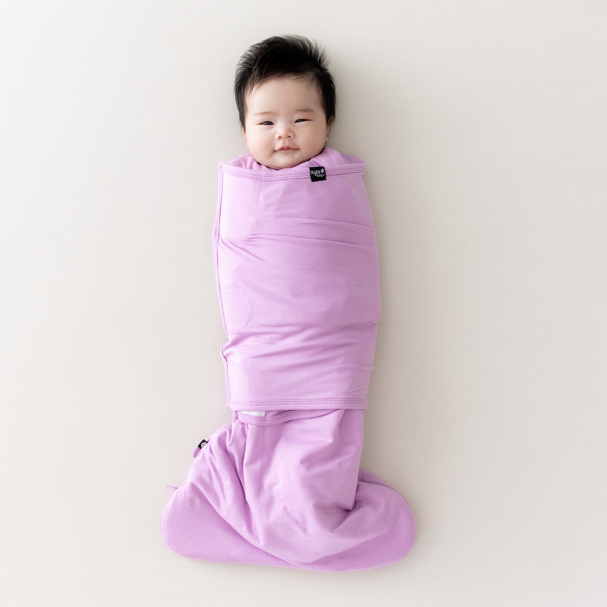 Baby swaddled in a Sleep bag swaddler in poi purple
