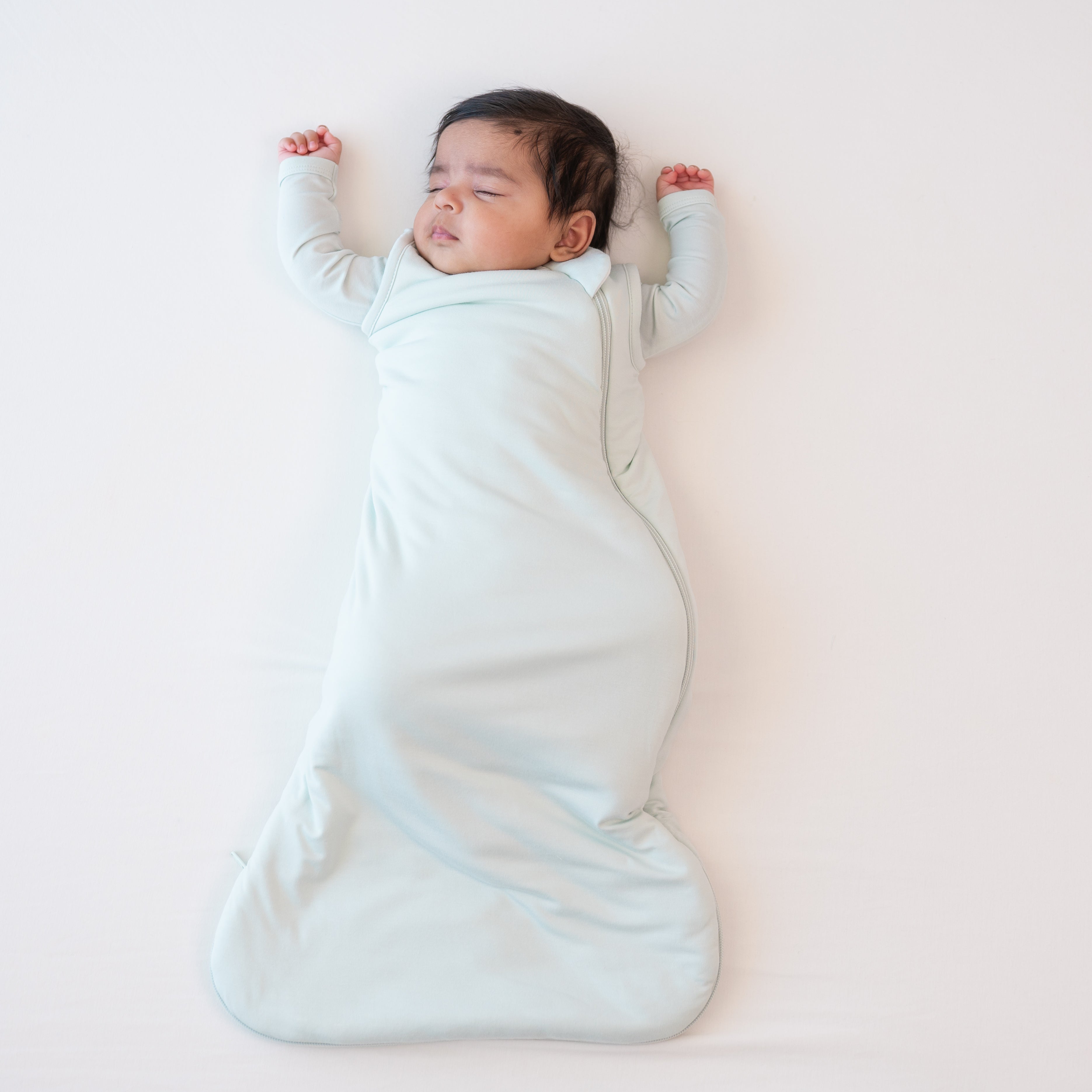 Sleeping infant wearing the Sleep Bag in Dew 1.0 with matching romper