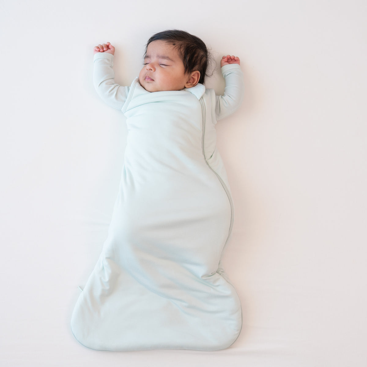 Sleeping infant wearing the Sleep Bag in Dew 1.0 with matching romper