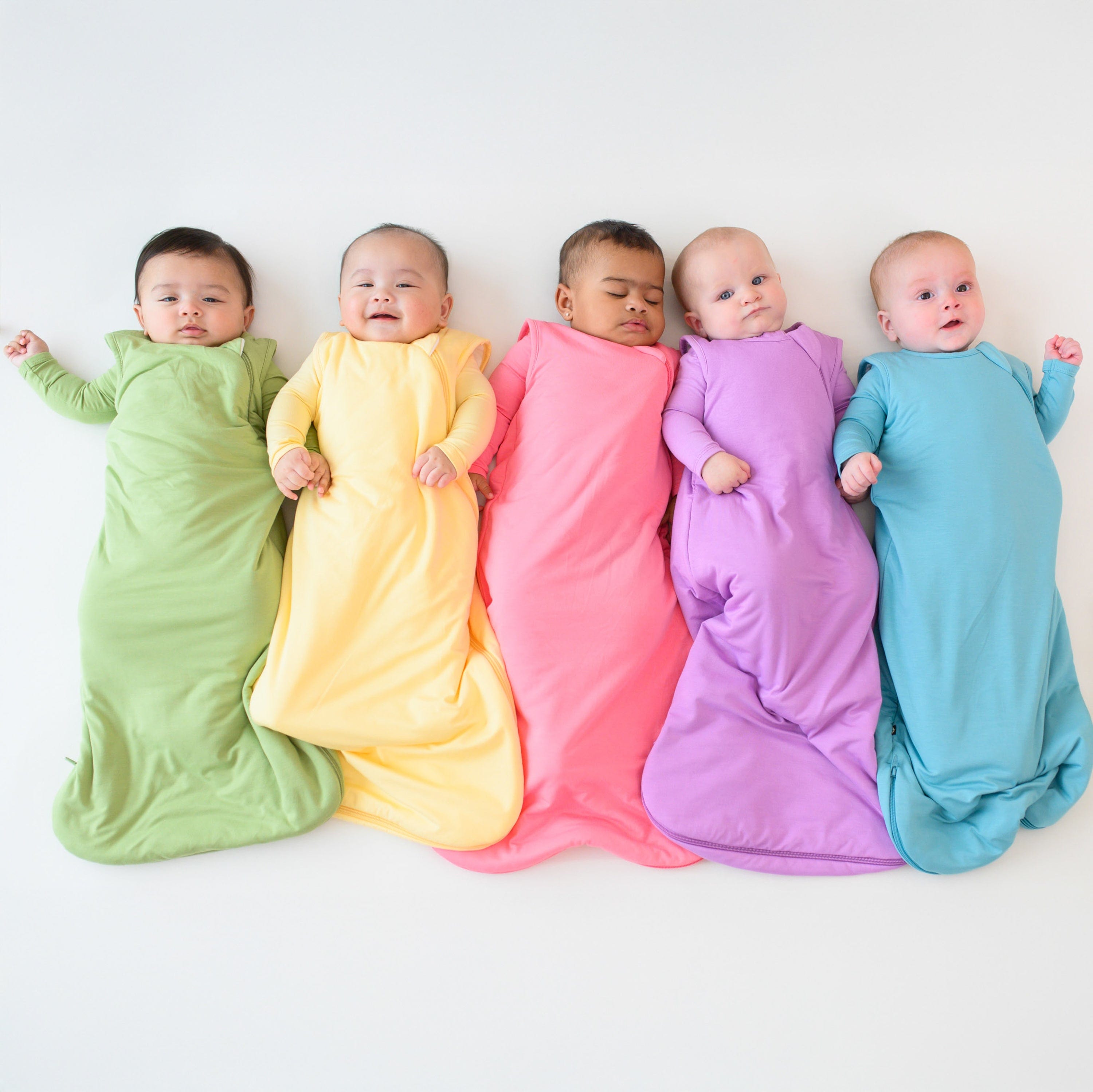 group of 5 babies wearing 1.0 sleep bags from kyte baby in new spring 2025 solids